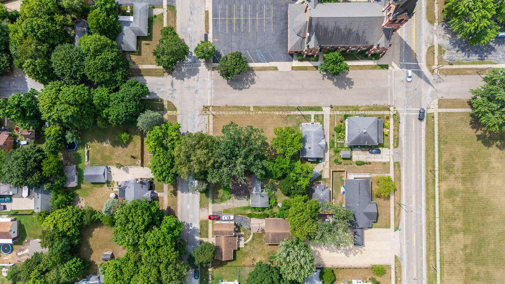Aerial view of a residential block with homes, tree-lined streets, and a large parking lot.