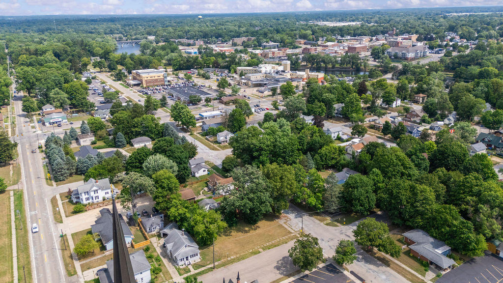 Aerial view of a leafy town with residential blocks, a main road, and a river.