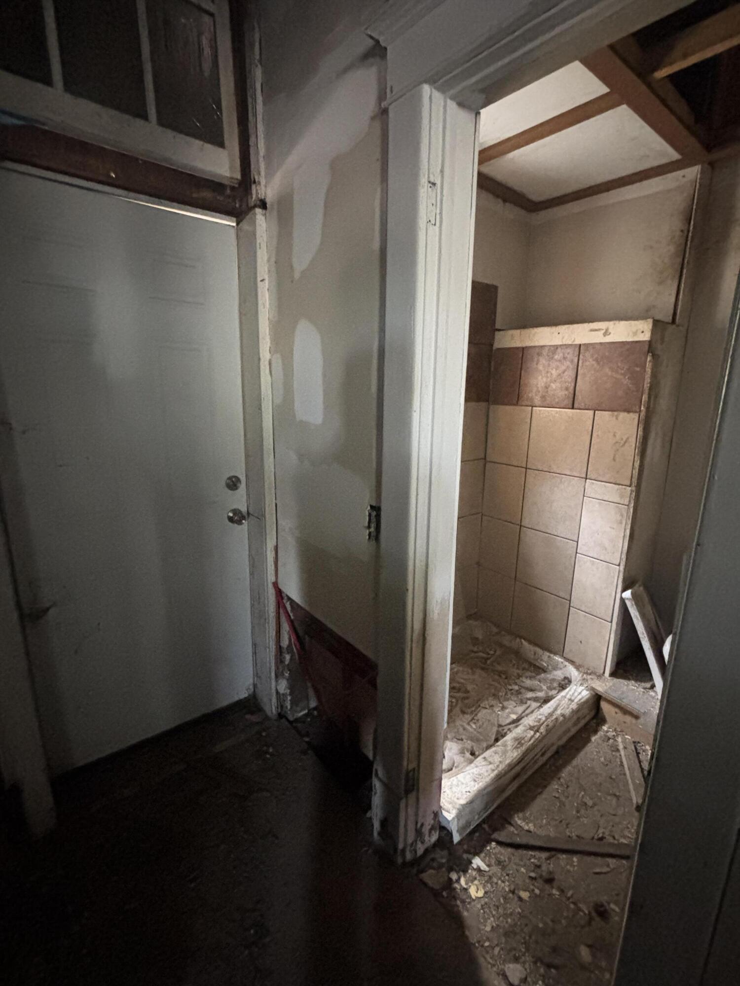 Unfinished bathroom with a tiled shower stall and debris across the floor.