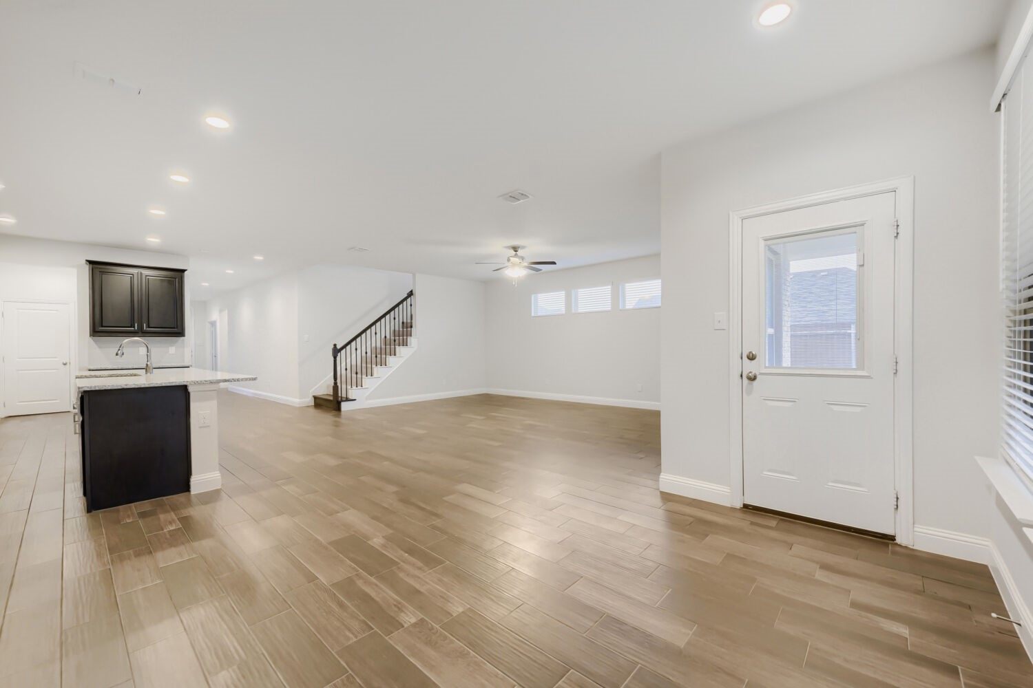 Open living area with tiled floors, a kitchen peninsula, and staircase.