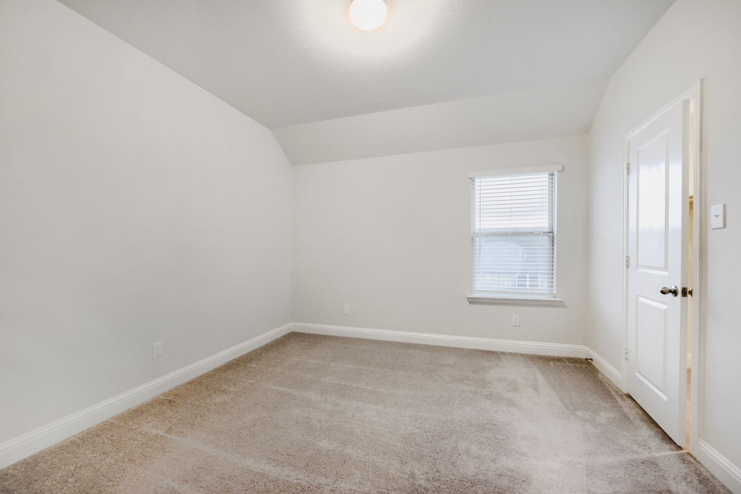 Empty carpeted room with a single window and an open doorway.