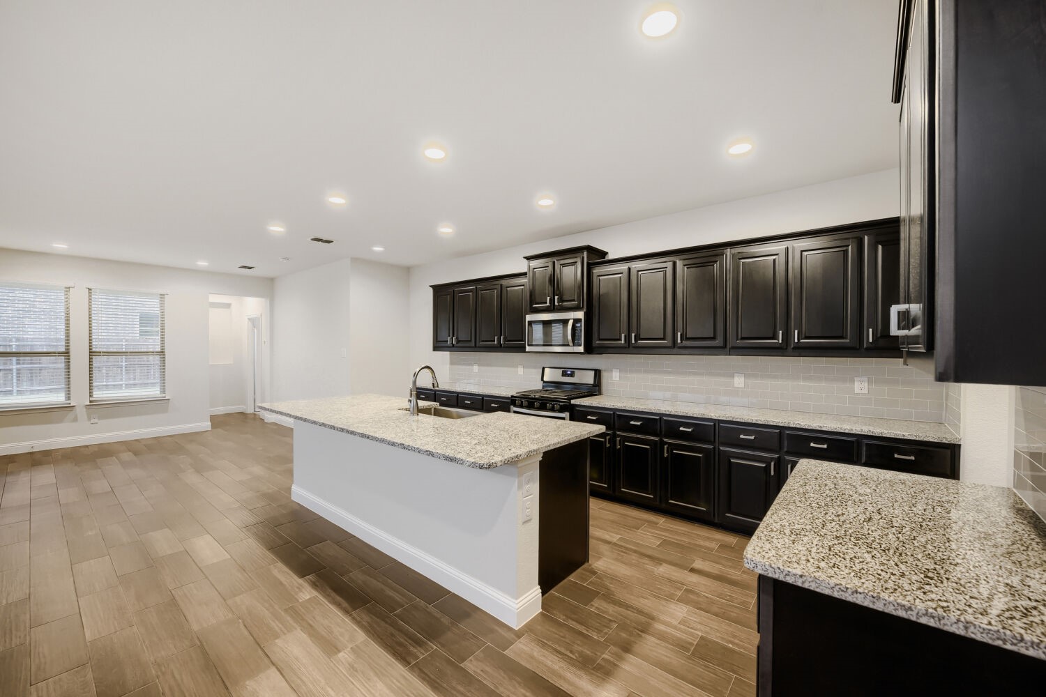 Kitchen with dark cabinets, granite counters, a large island, and an adjoining dining area.