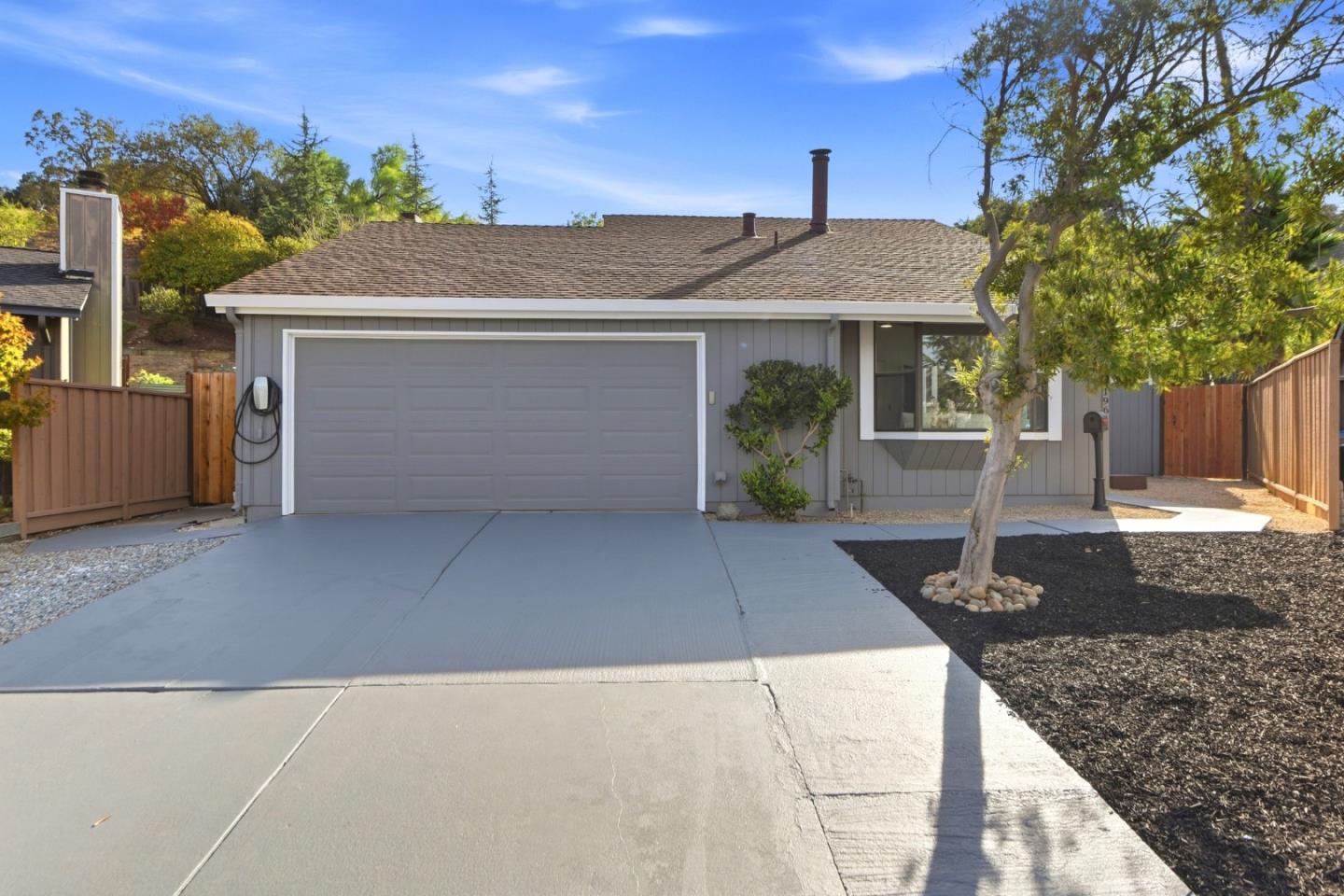 Gray single-story home with a double garage, broad driveway, and wood fencing.