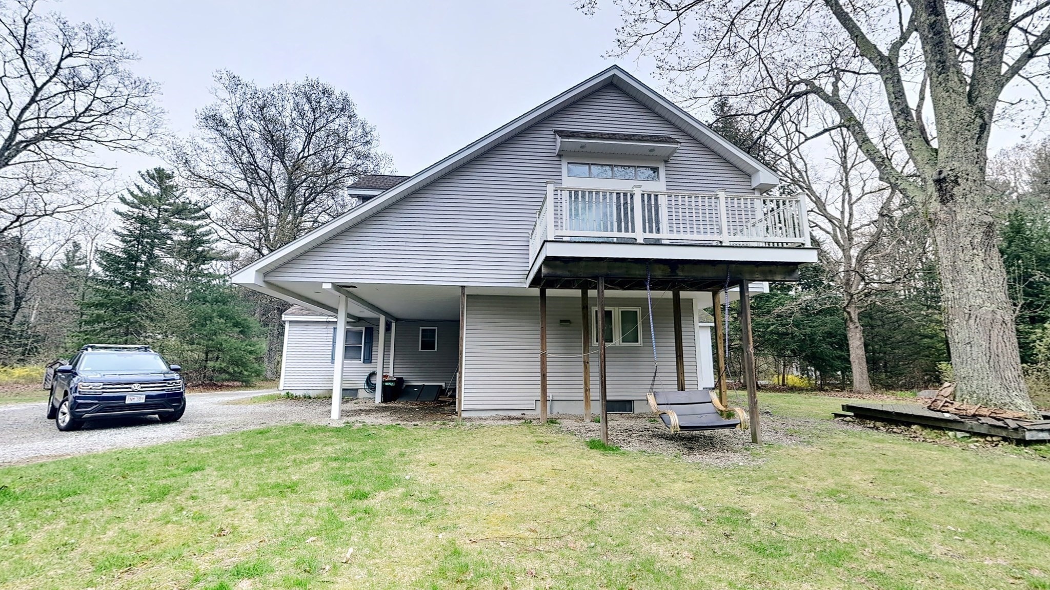 Gray house with a raised balcony, covered lower patio, and hanging swing