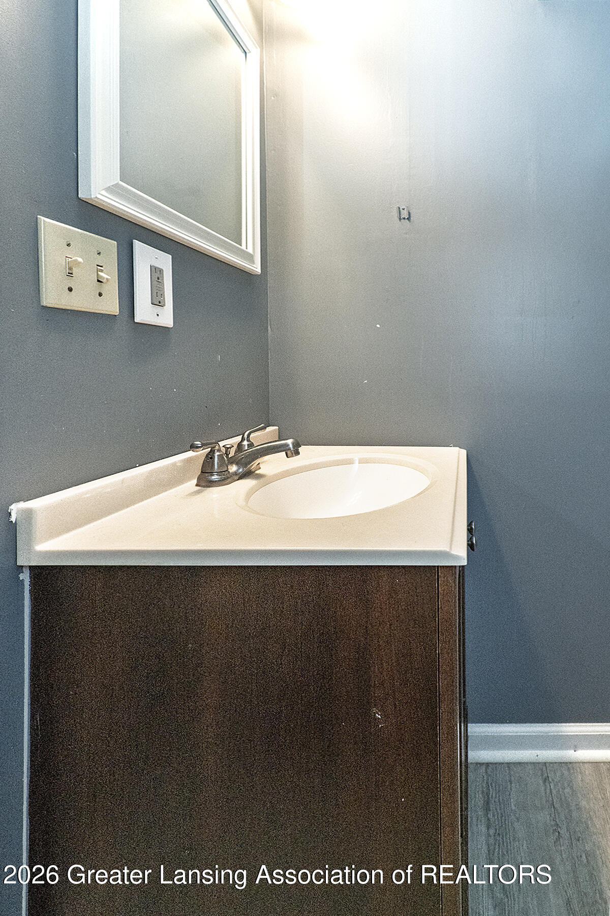 Bathroom vanity with an oval sink, chrome faucet, and dark wood cabinet.