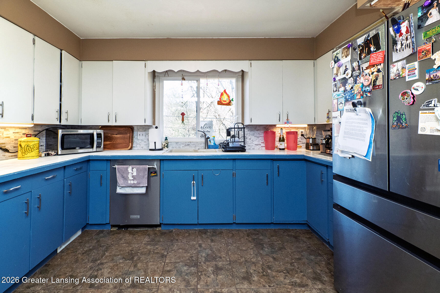 Kitchen with bright blue cabinets, white upper cabinets, and a window above the sink.