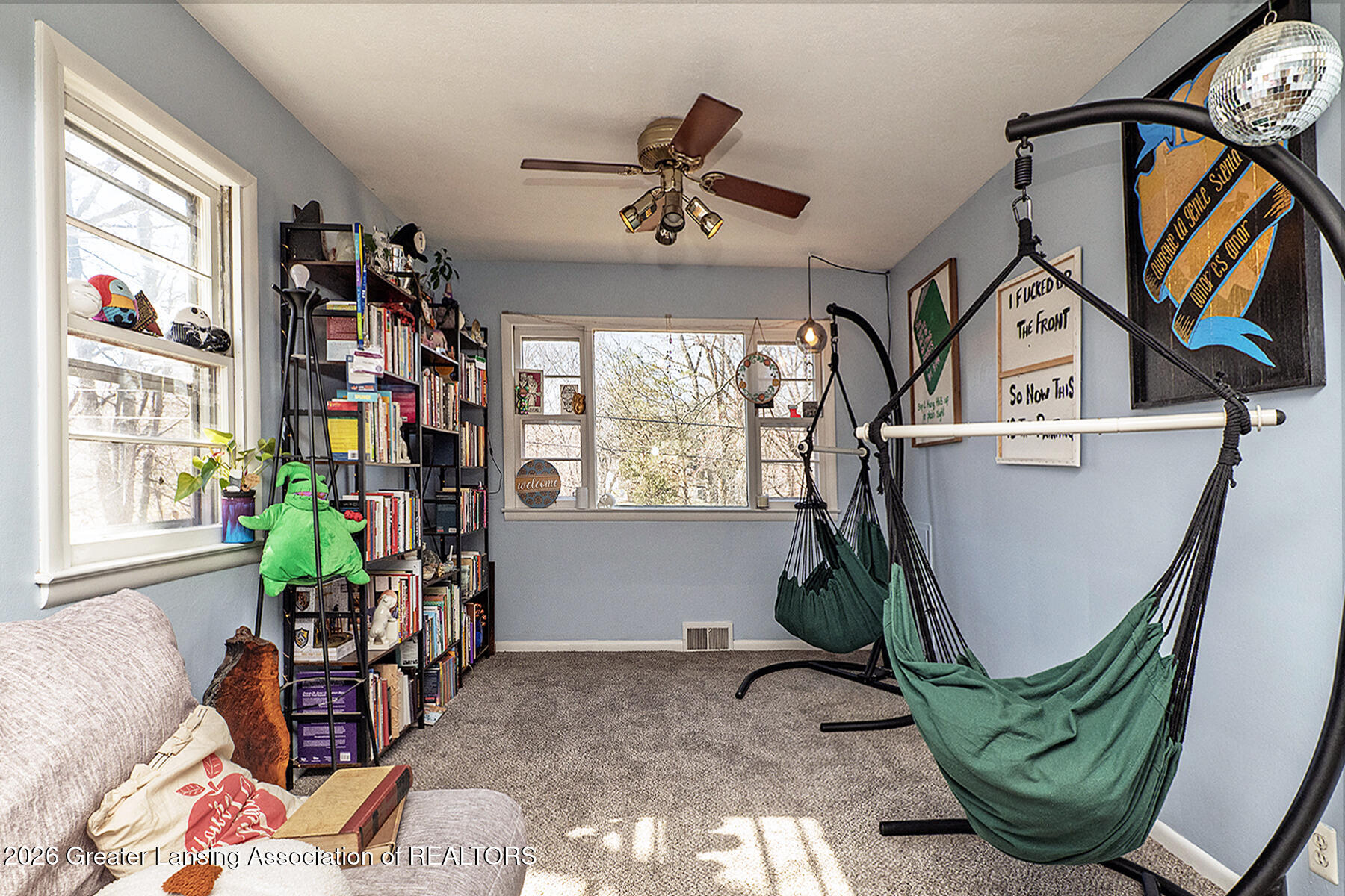 Bonus room with bookcases, large windows, and two green hammock chairs.