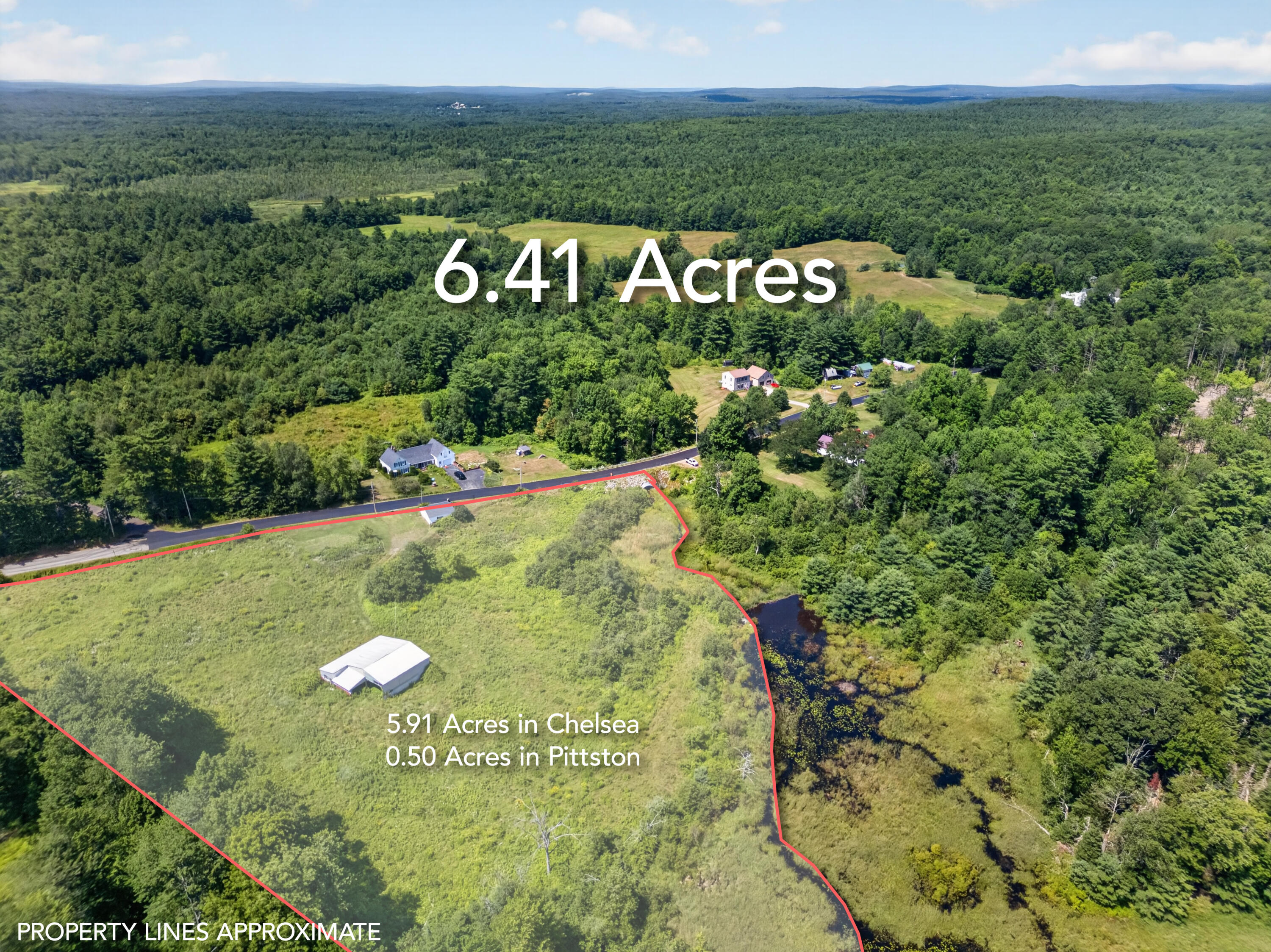 Aerial view of a grassy 6.41-acre lot outlined in red, bordered by woods and a small pond.