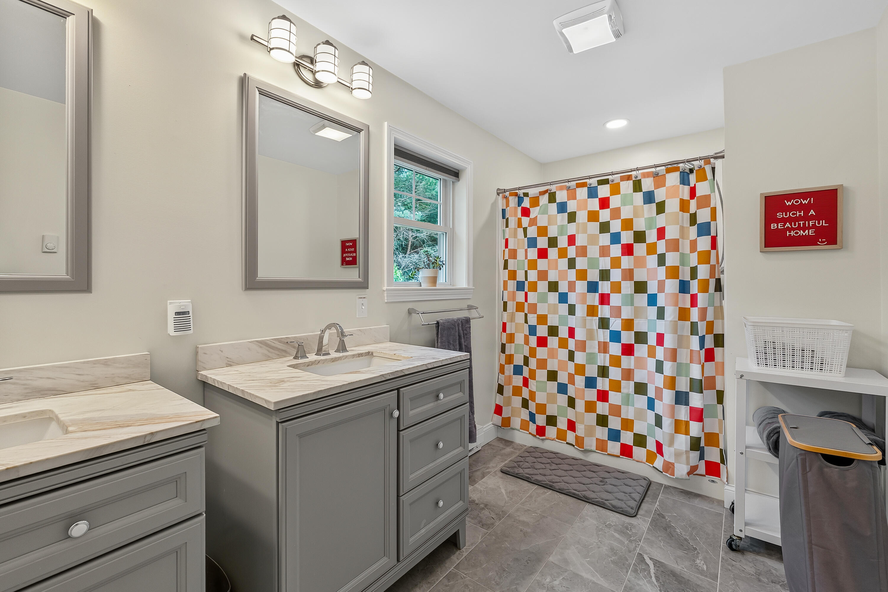 Bathroom with double gray vanities and a colorful checkerboard shower curtain.