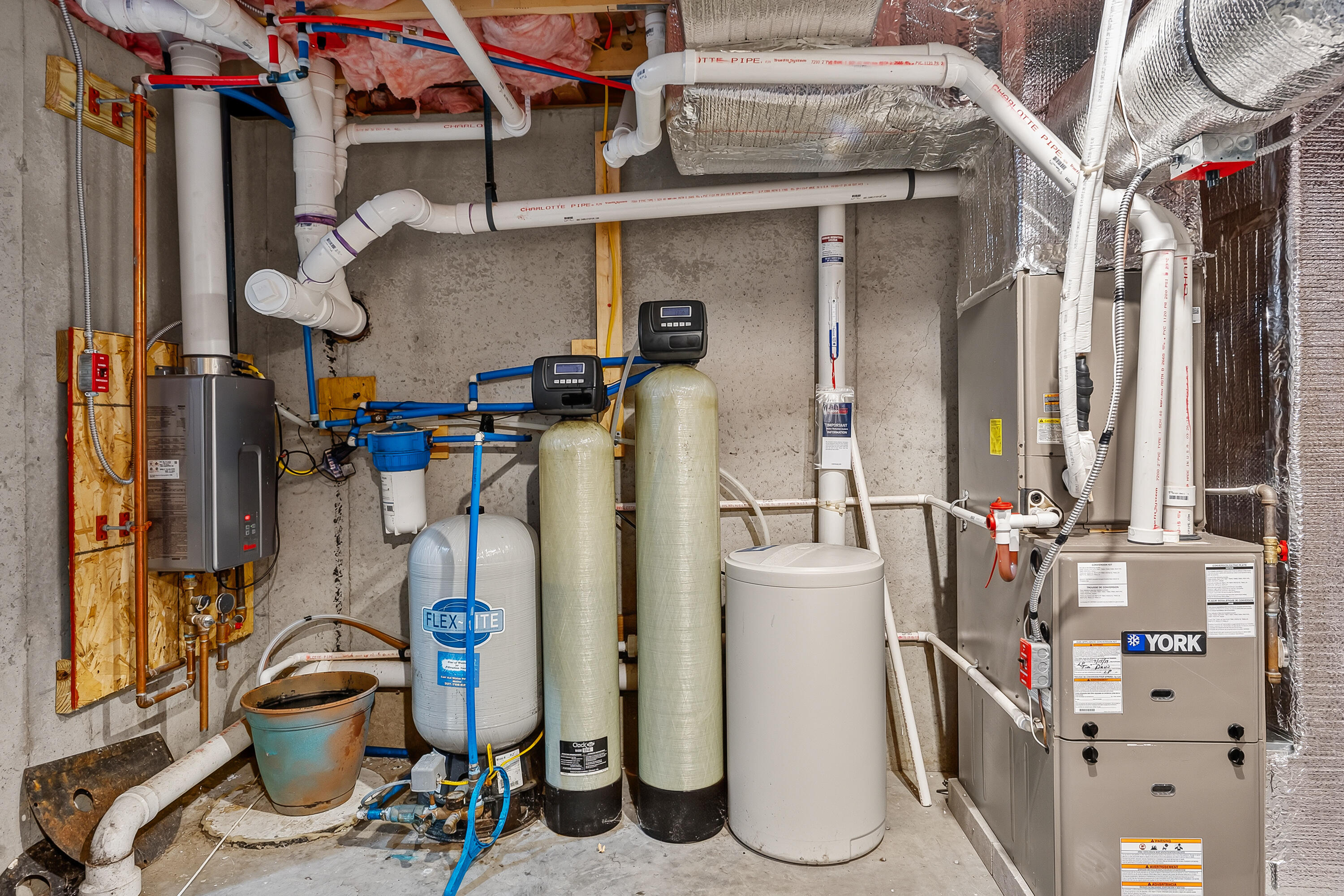 Basement mechanical room with a York furnace, water heater, and water filtration tanks.