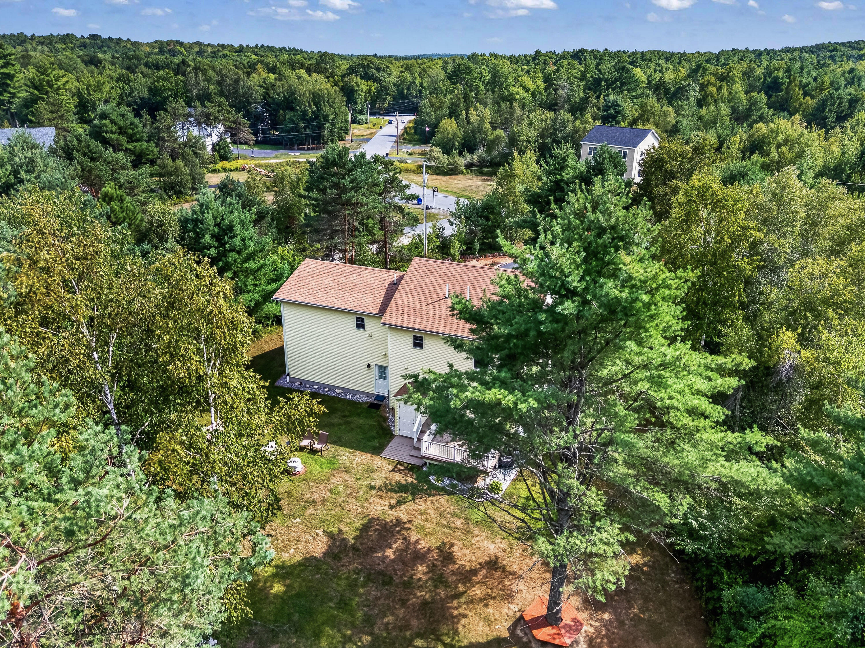 Aerial view of a two-story home and deck nestled among mature trees.