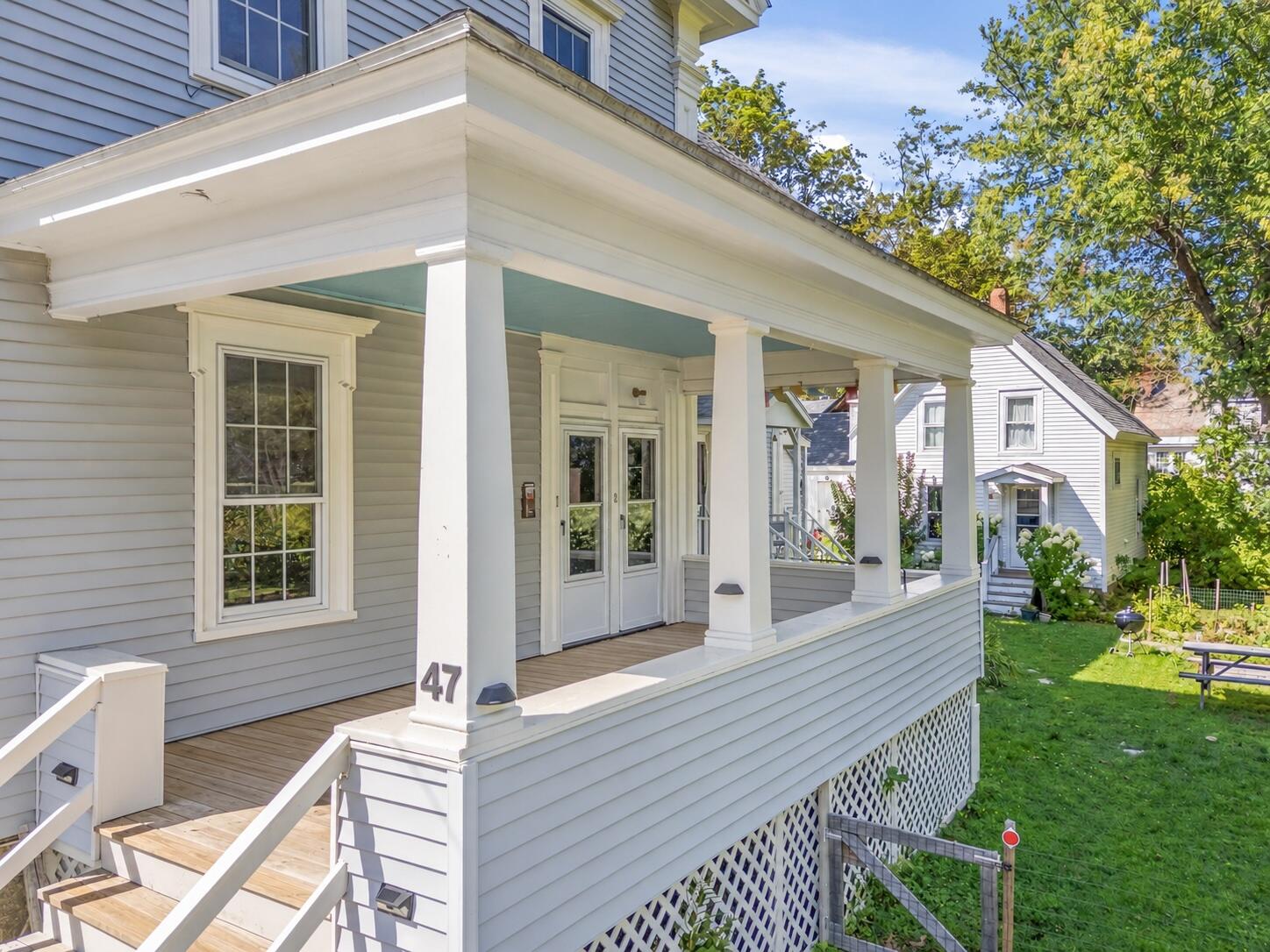 Gray clapboard house with a wide covered porch, white columns, and front steps.