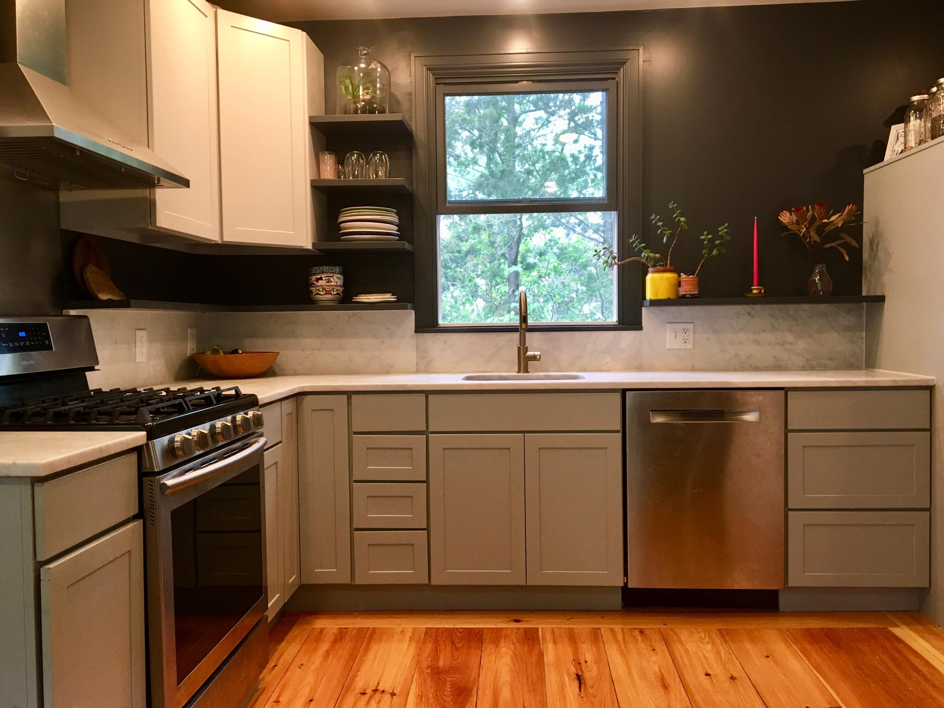 Kitchen with a large tree-framed window above the sink and warm wood floors.