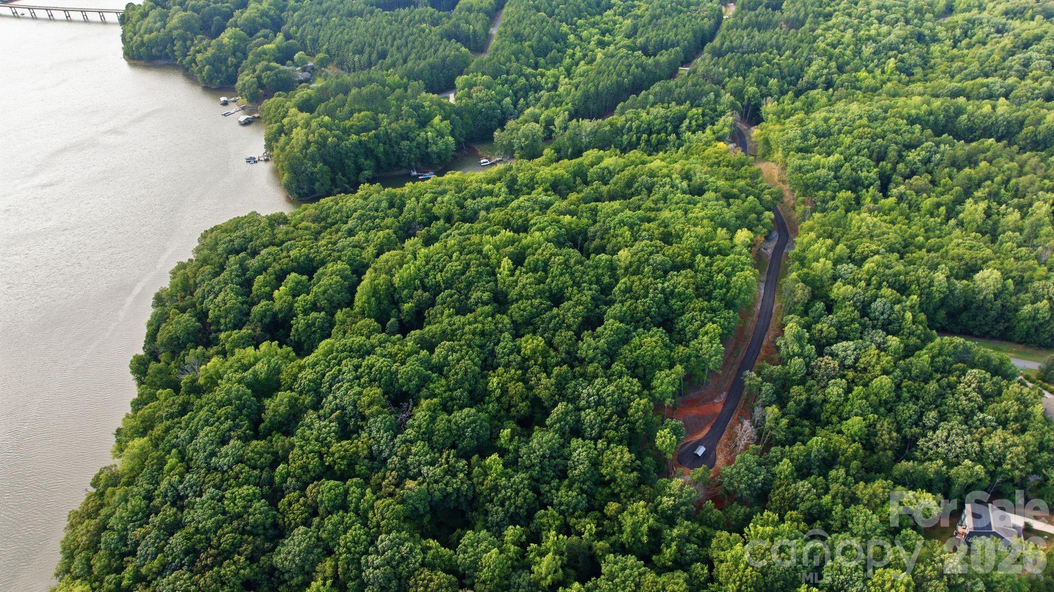 Aerial view of wooded waterfront land with a winding access road and lake coves.