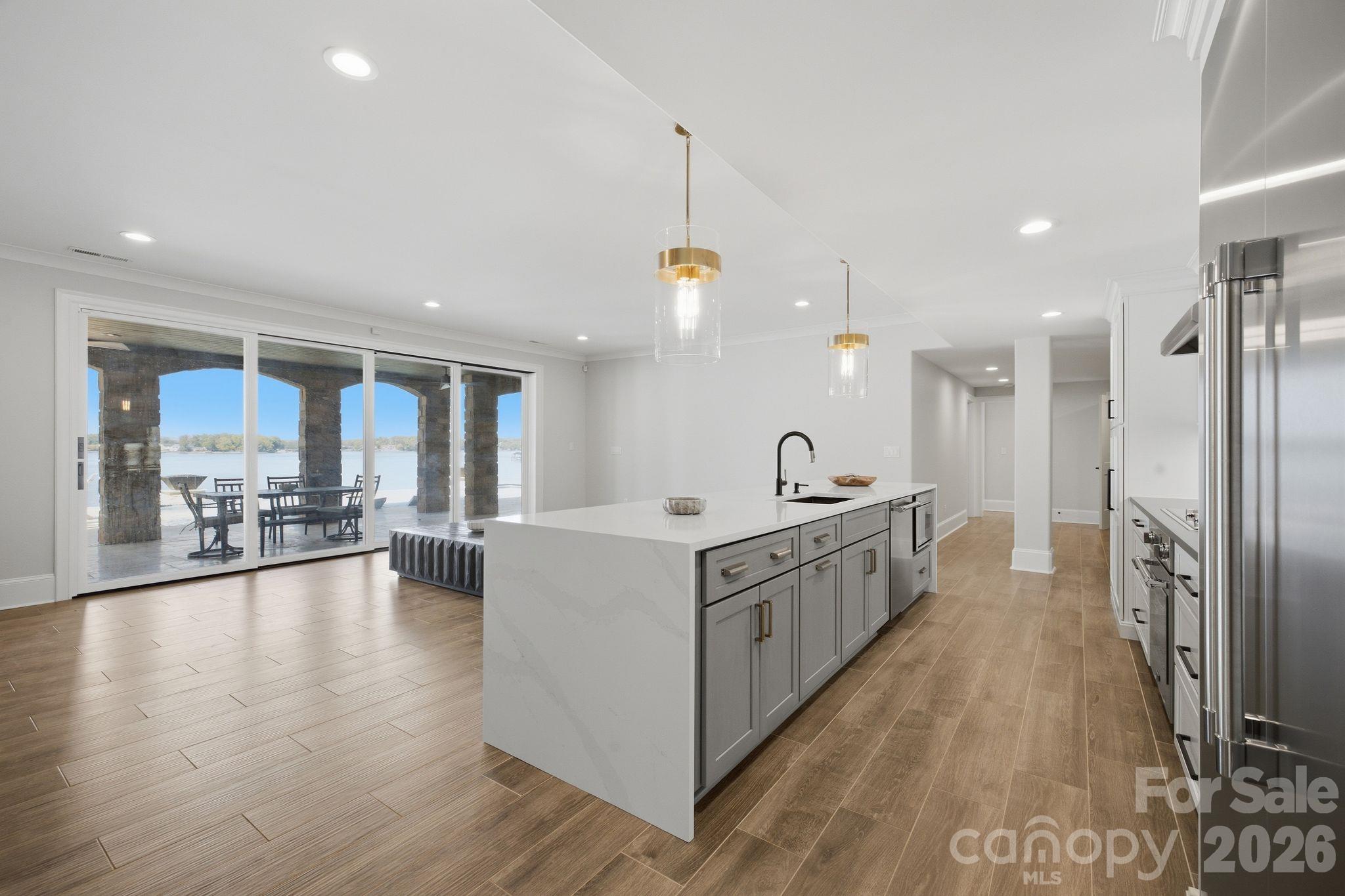 Modern kitchen with a large island and sliding doors opening to a covered patio overlooking the water.