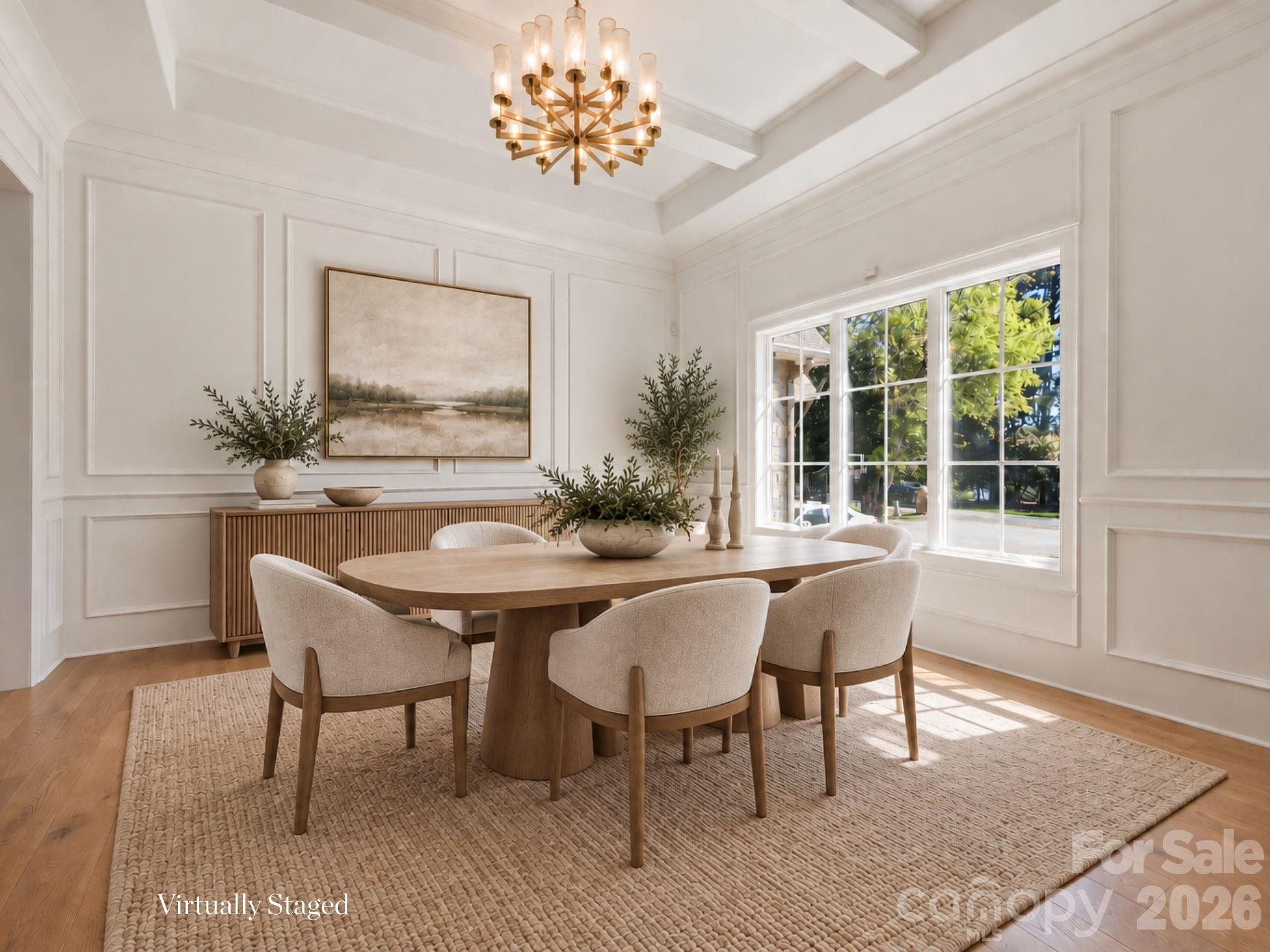 Virtually staged dining room with a rounded wood table, upholstered chairs, and a brass chandelier.