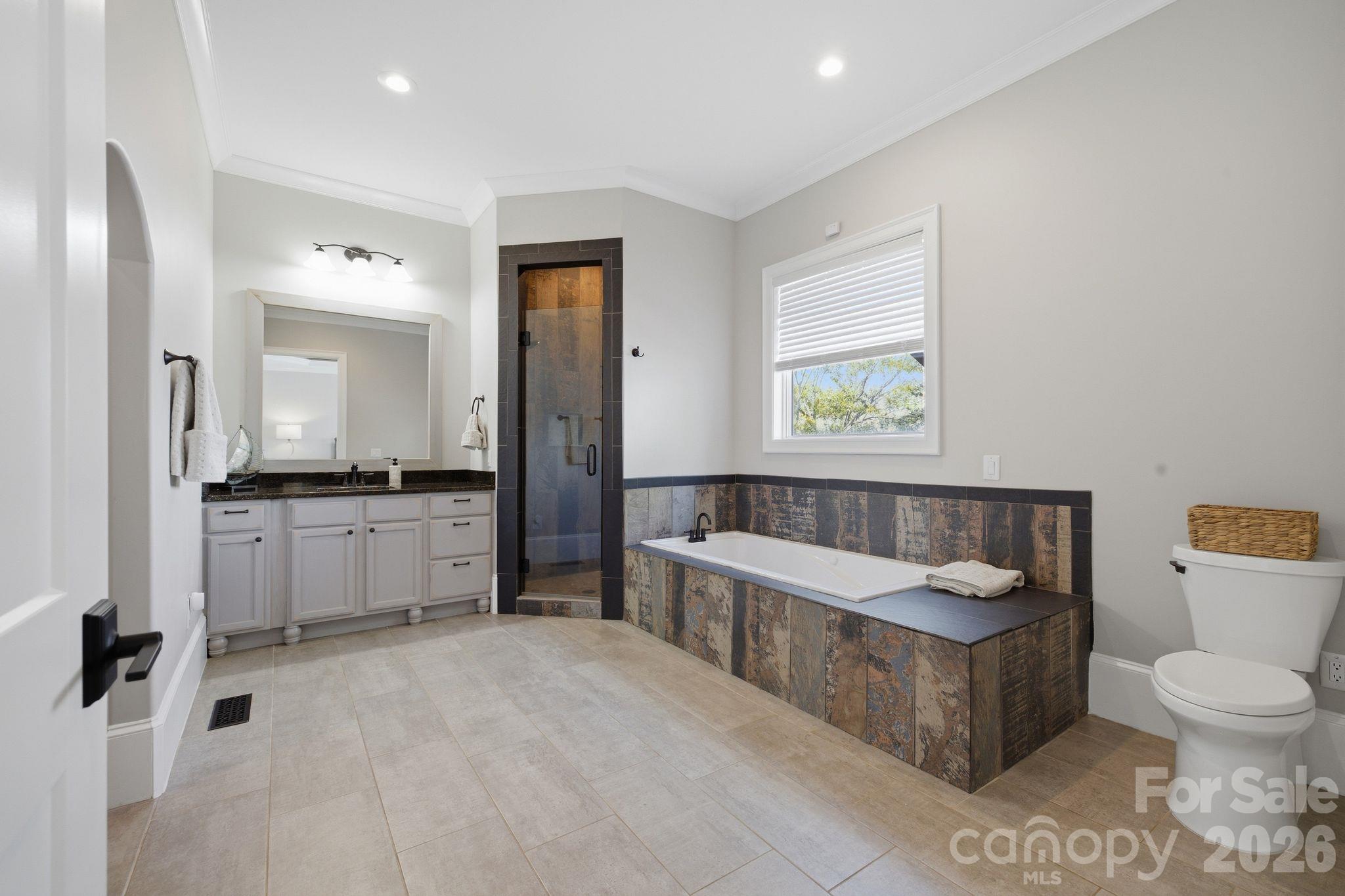 Bathroom with a built-in soaking tub, glass shower, and white vanity.