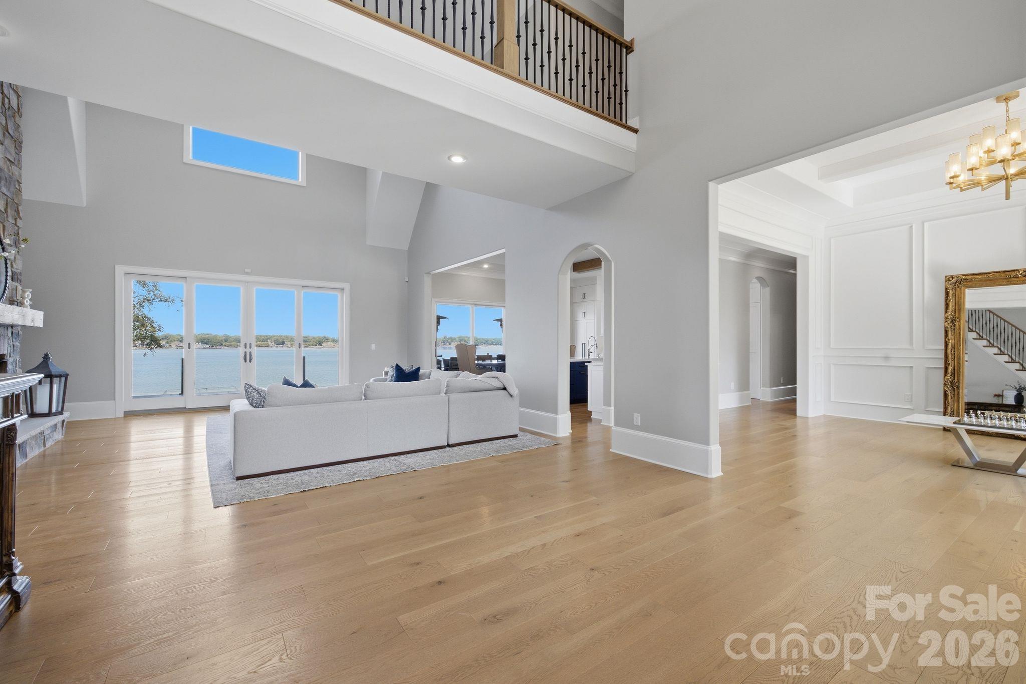 Living room with a white sectional, stone fireplace, and lake views through sliding glass doors.
