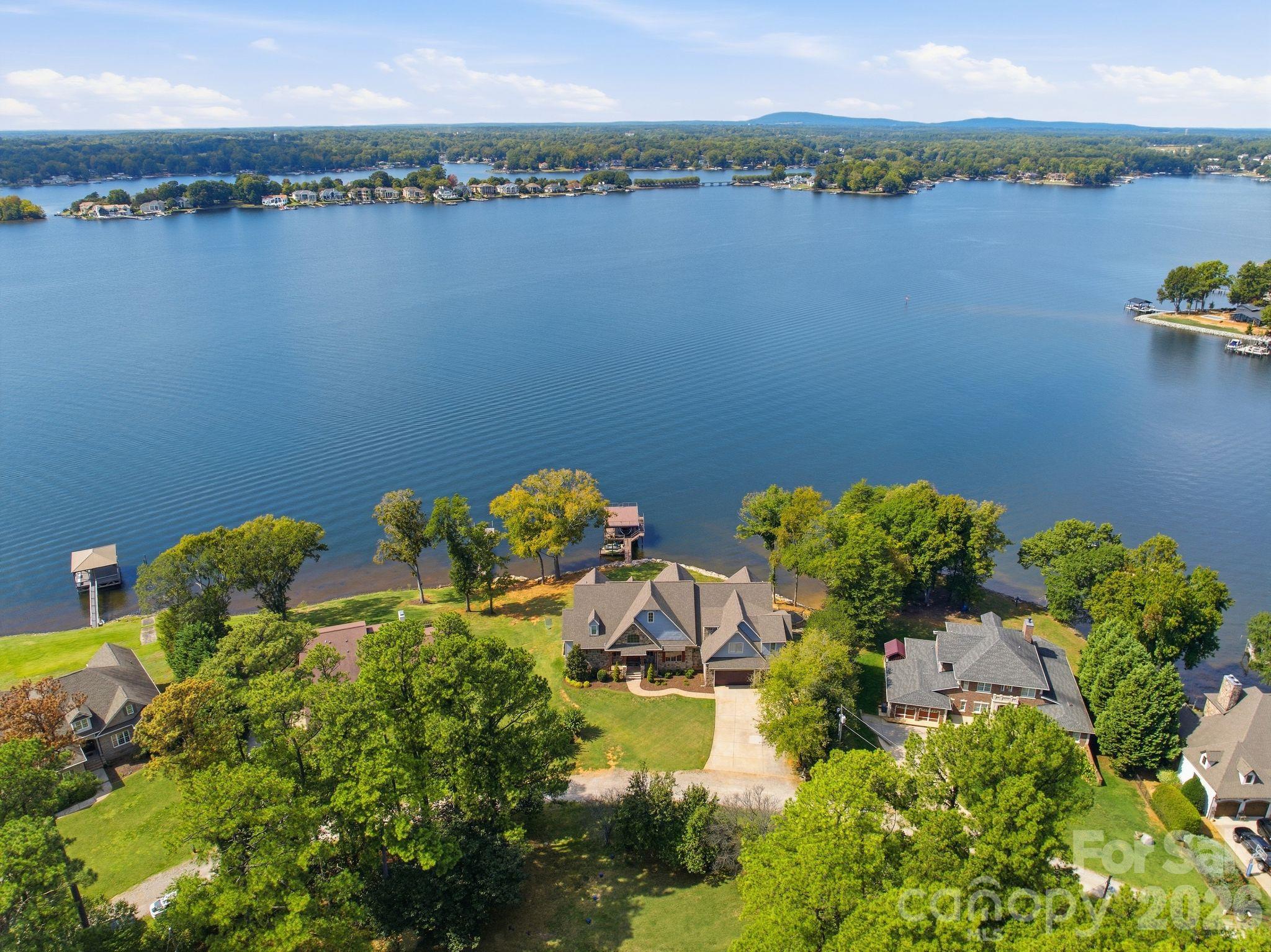 Aerial view of 112 Birdsong Lane, with a broad lakefront lawn and dock beside Lake Norman.