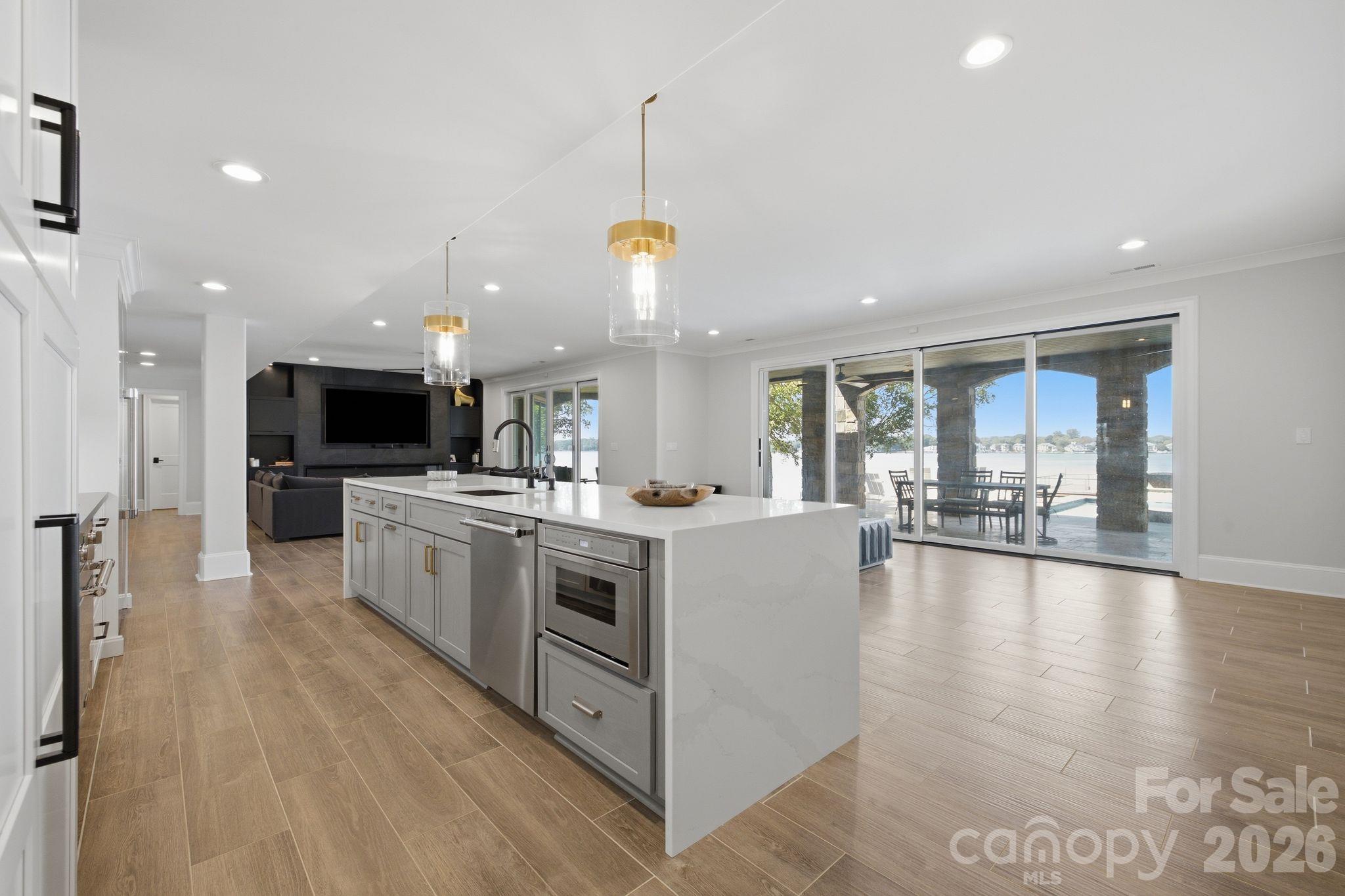 Open-plan kitchen with a large white island and sliding doors overlooking a lake.