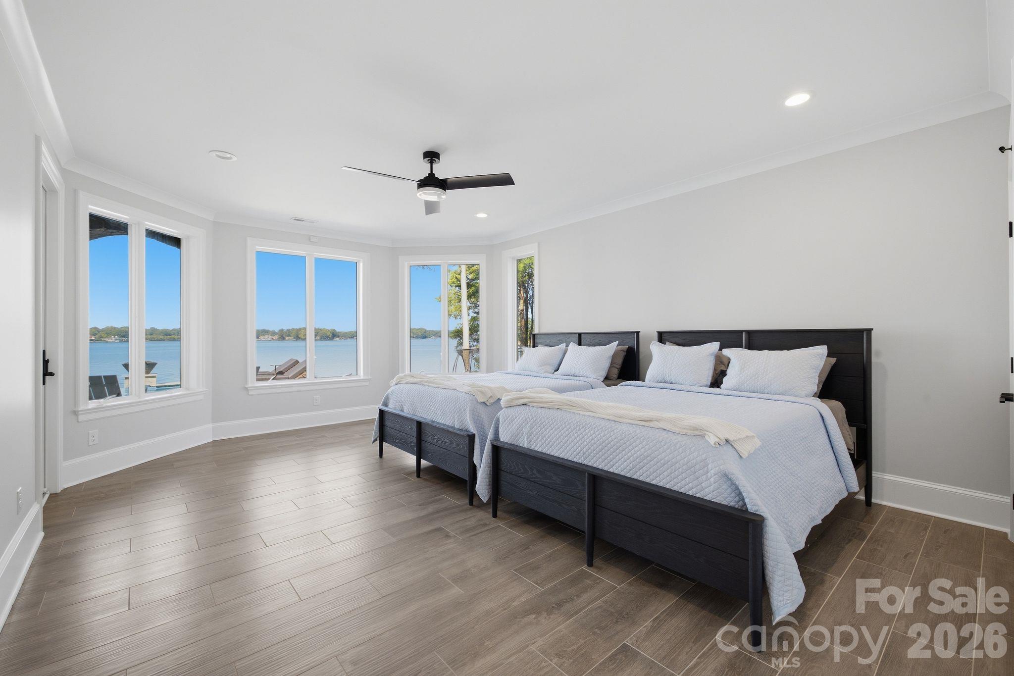 Bedroom with two beds and large windows overlooking the lake.