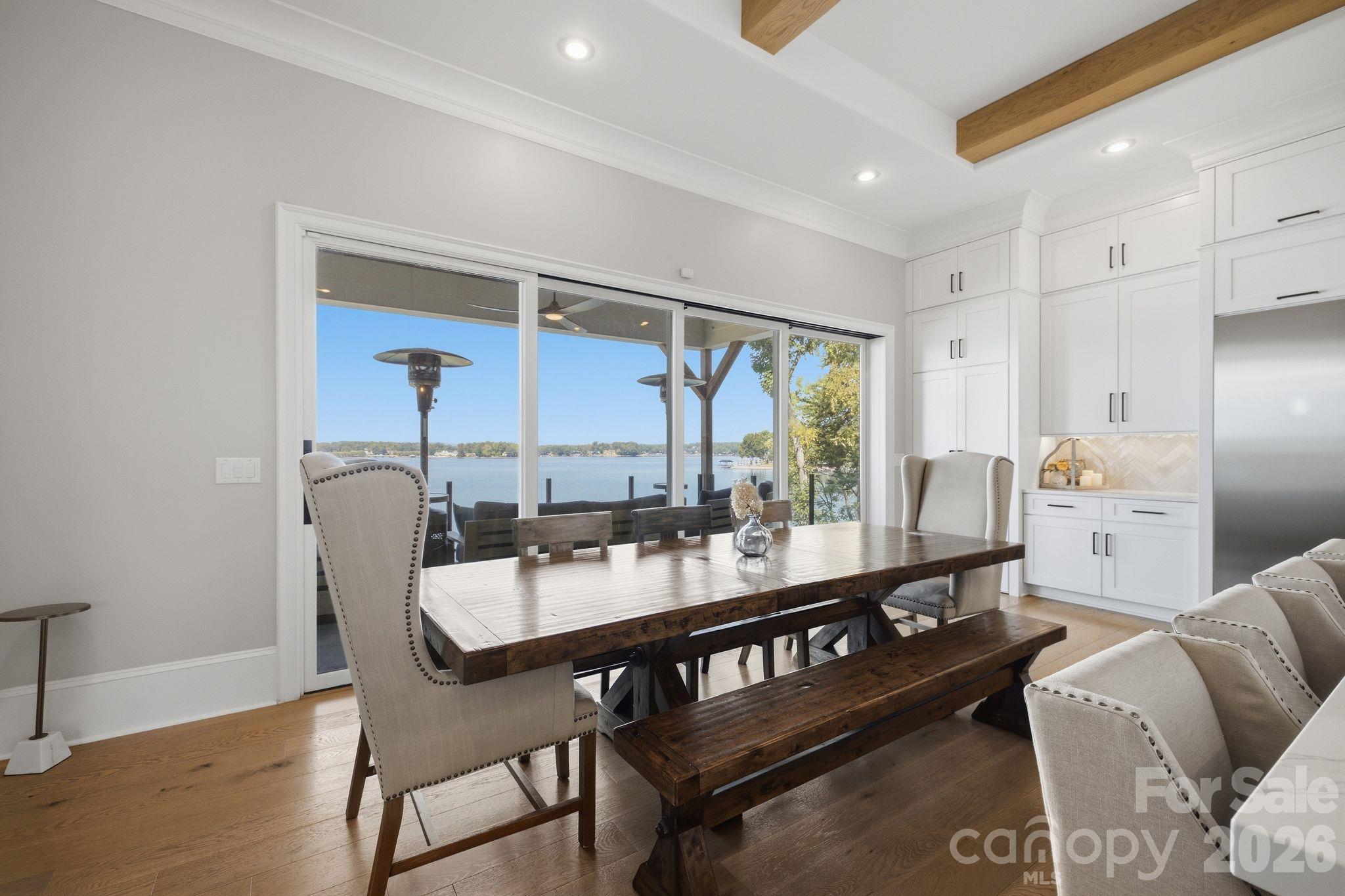 Dining area with a dark wood table and bench, white cabinetry, and sliding doors overlooking the lake.