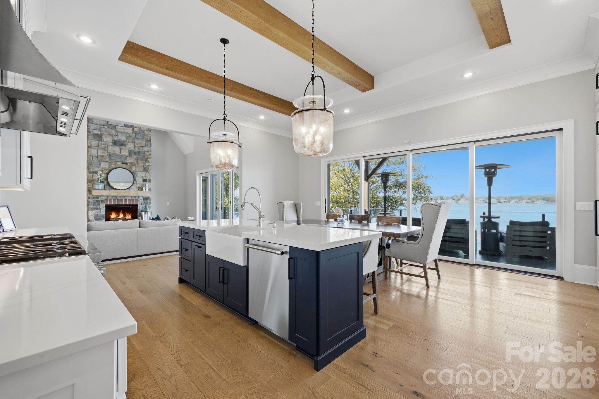 Open kitchen and living area with a navy island, stone fireplace, and lake views through sliding glass doors.