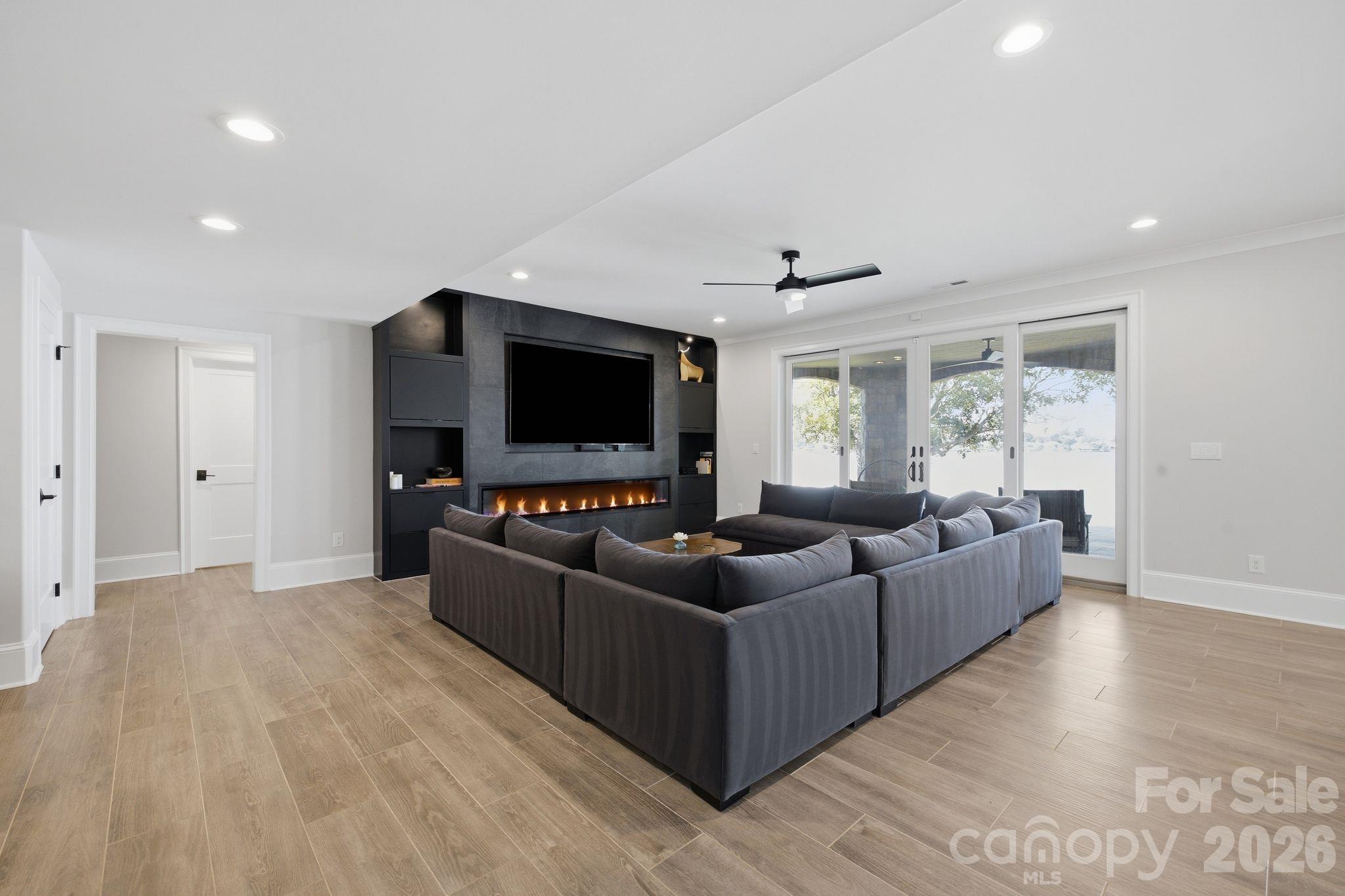 Living room with a gray sectional, built-in linear fireplace, and sliding doors overlooking the water.