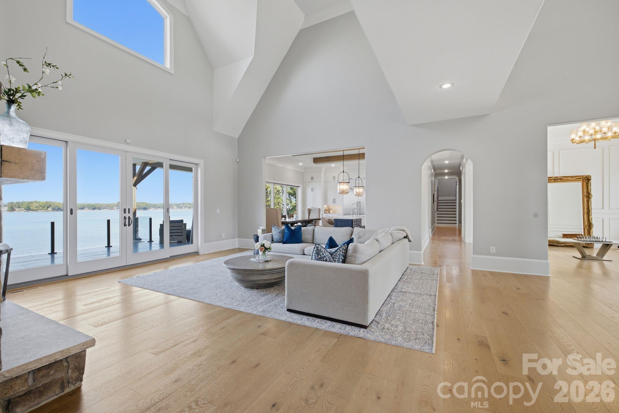 Staged living room with a vaulted ceiling, lakefront windows, and a white sectional sofa.