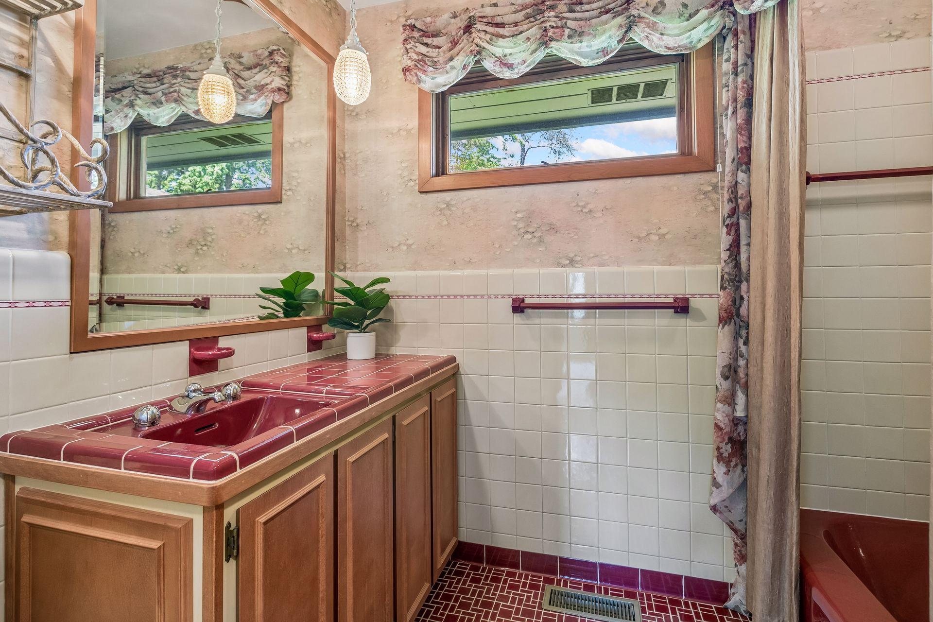 Bathroom with a red tiled vanity, matching sink, wood cabinetry, and floral curtains.