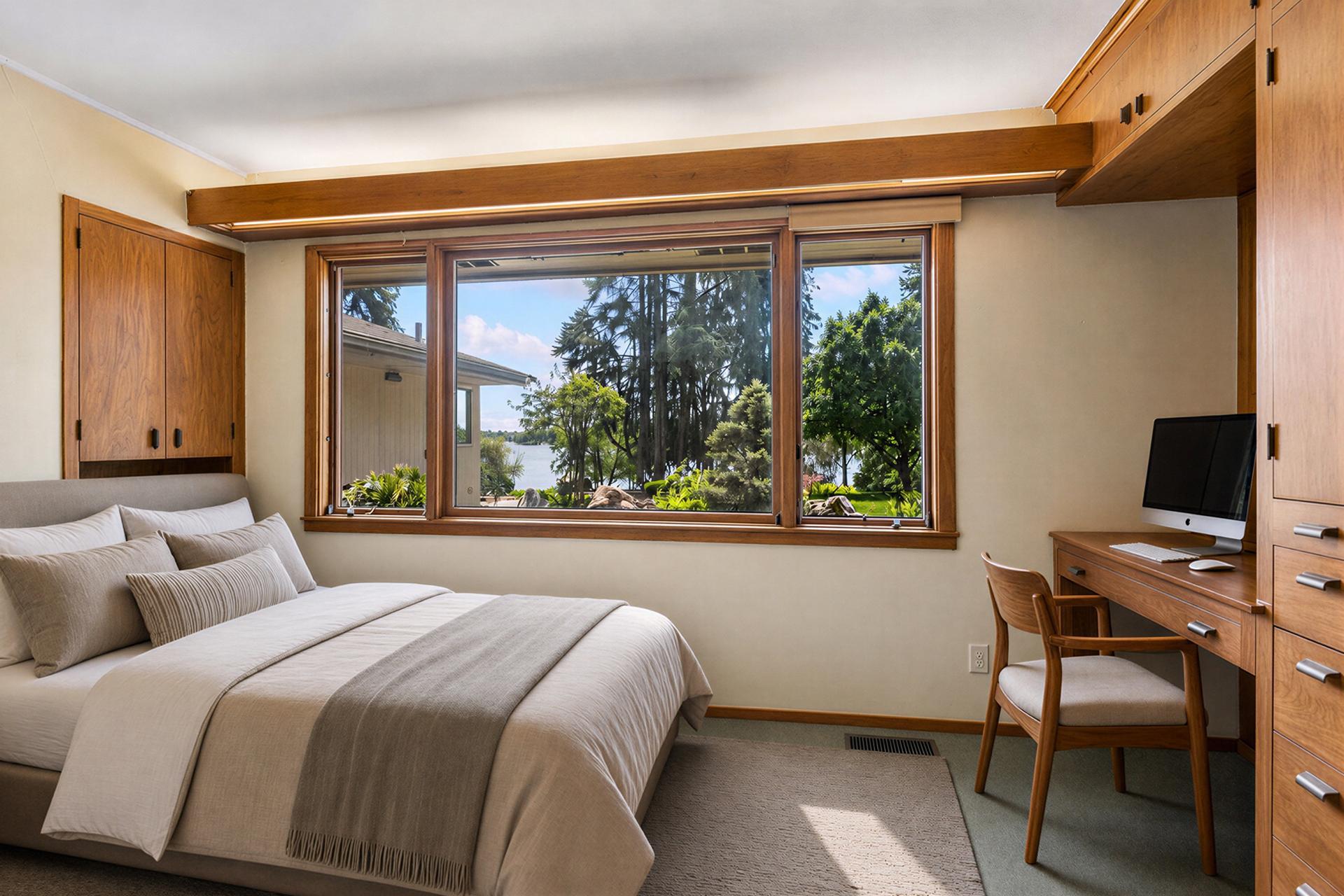 Bedroom with built-in wood cabinetry and a wide window overlooking a lake.