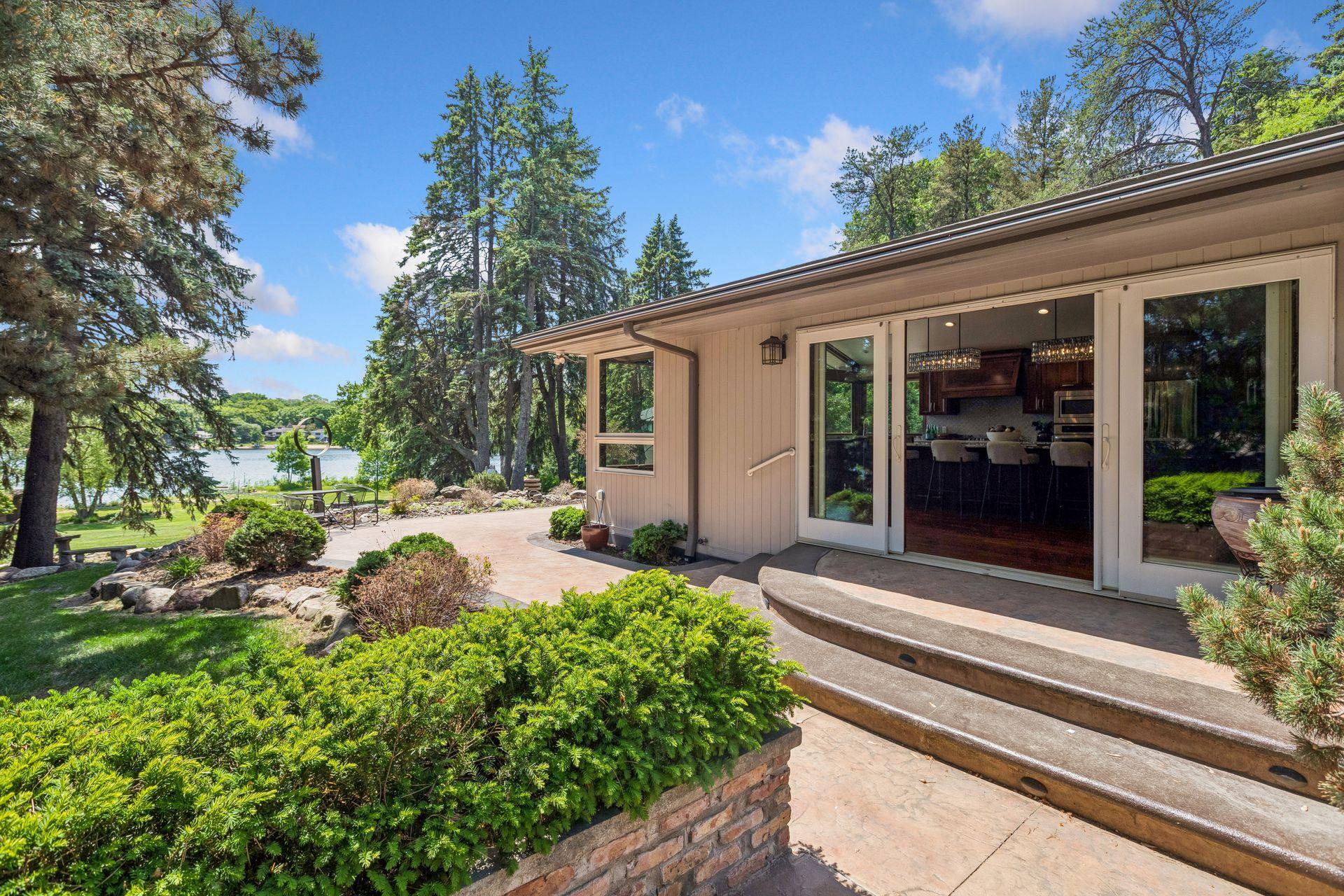 Home patio with sliding glass doors, landscaped garden, and a lake view.
