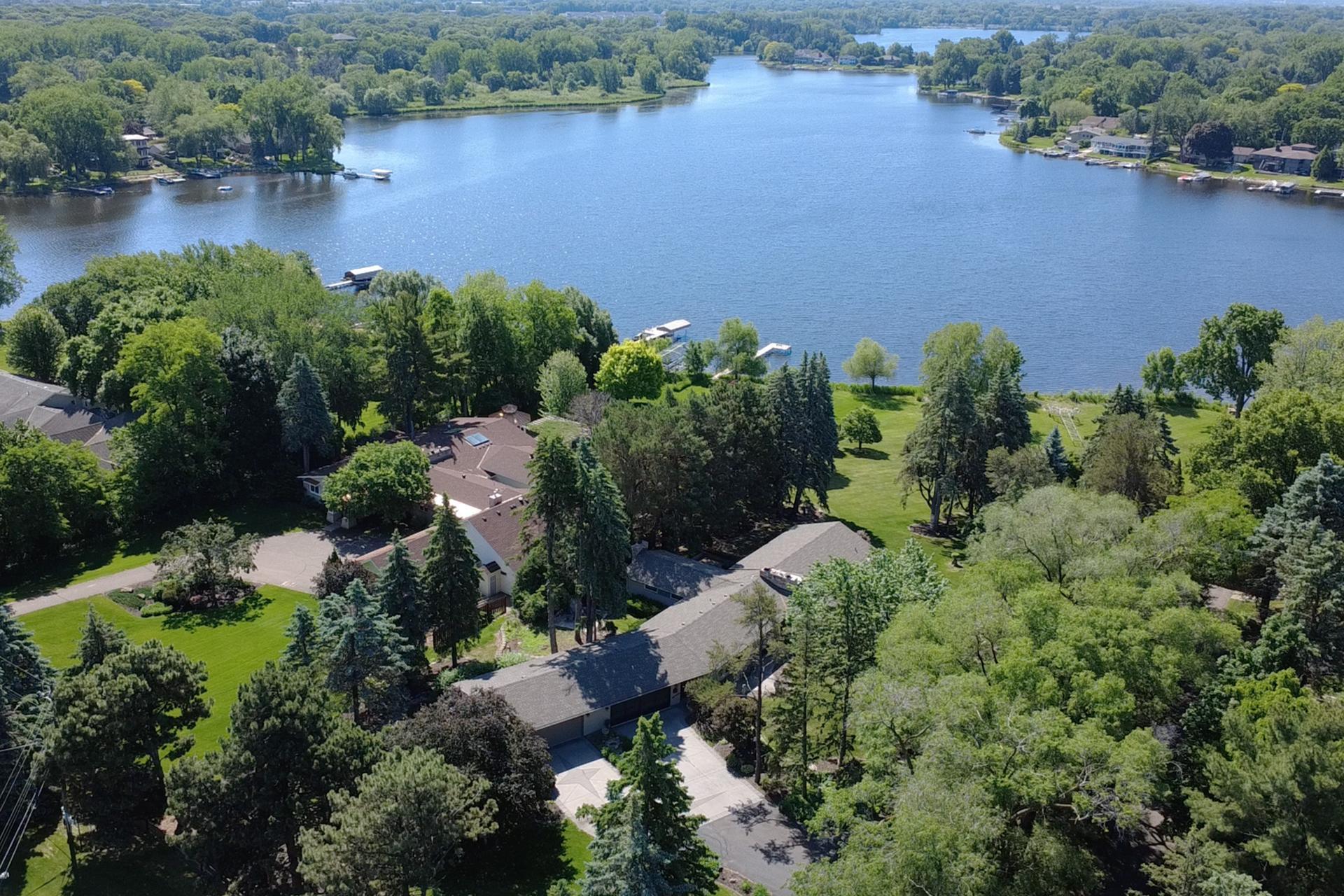 Aerial view of lakeside homes and tree-lined shore with several docks.