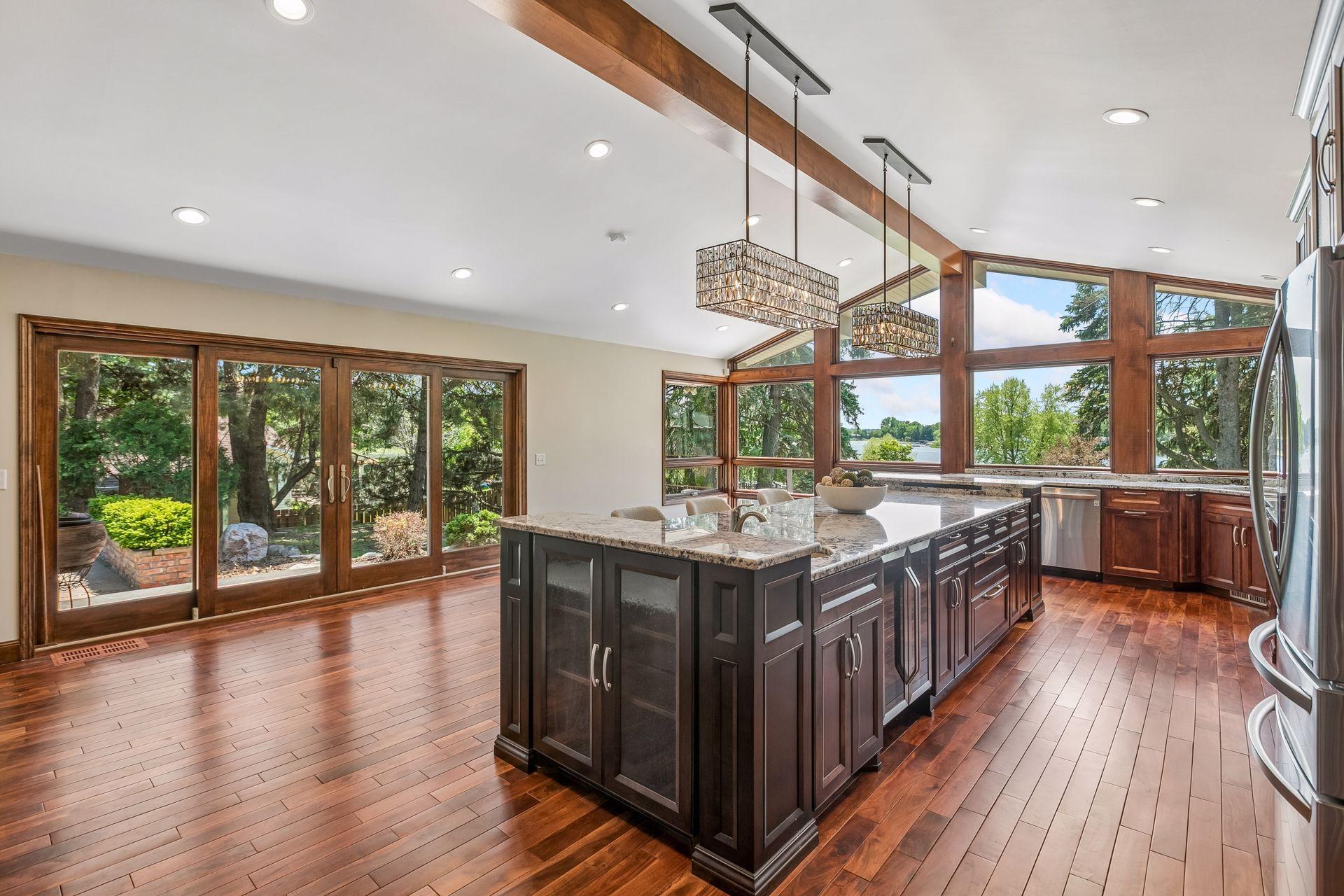 Kitchen with a large granite island, wood cabinetry, and expansive windows overlooking the lake.