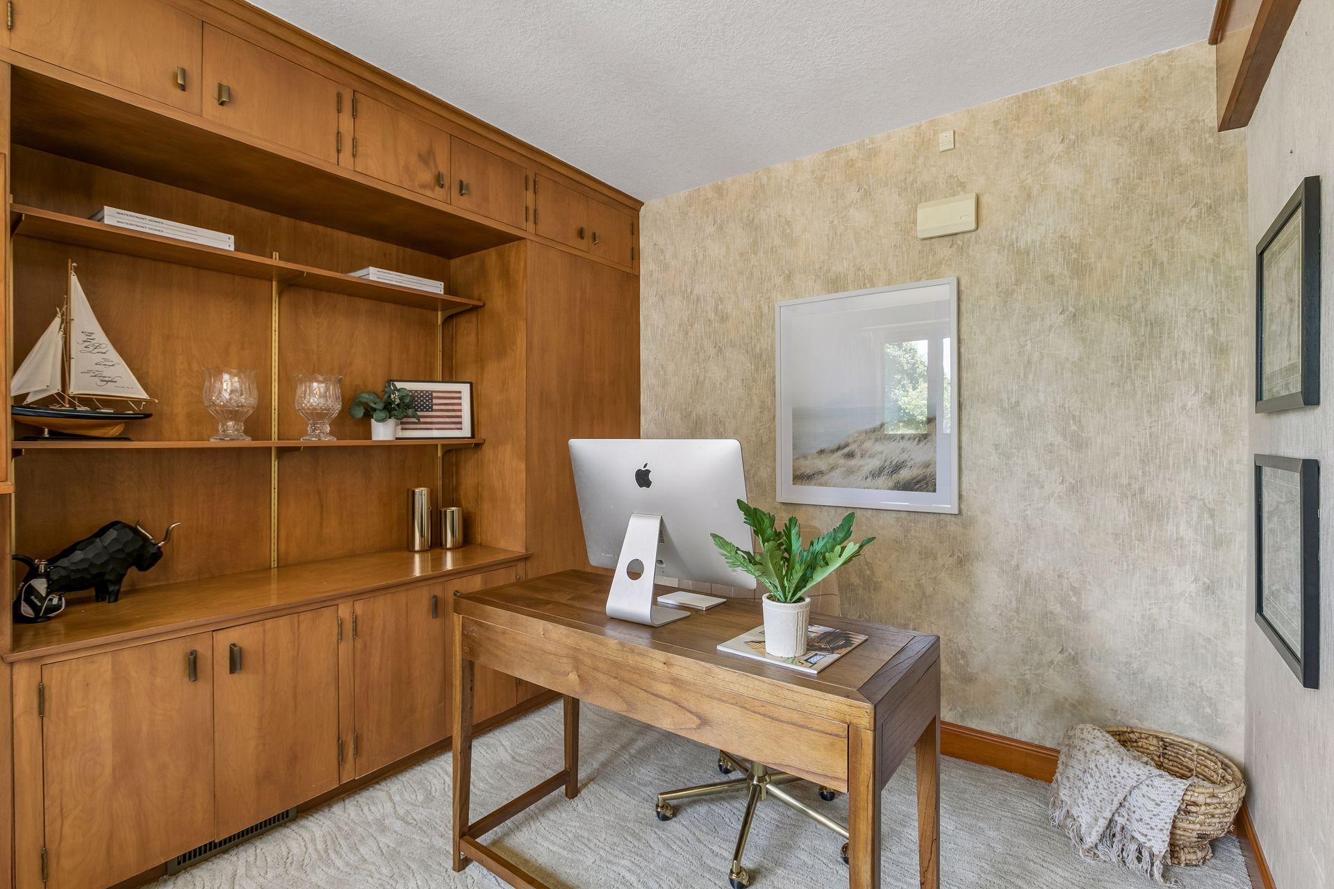 Home office with built-in wood cabinetry and a desk with an Apple computer.
