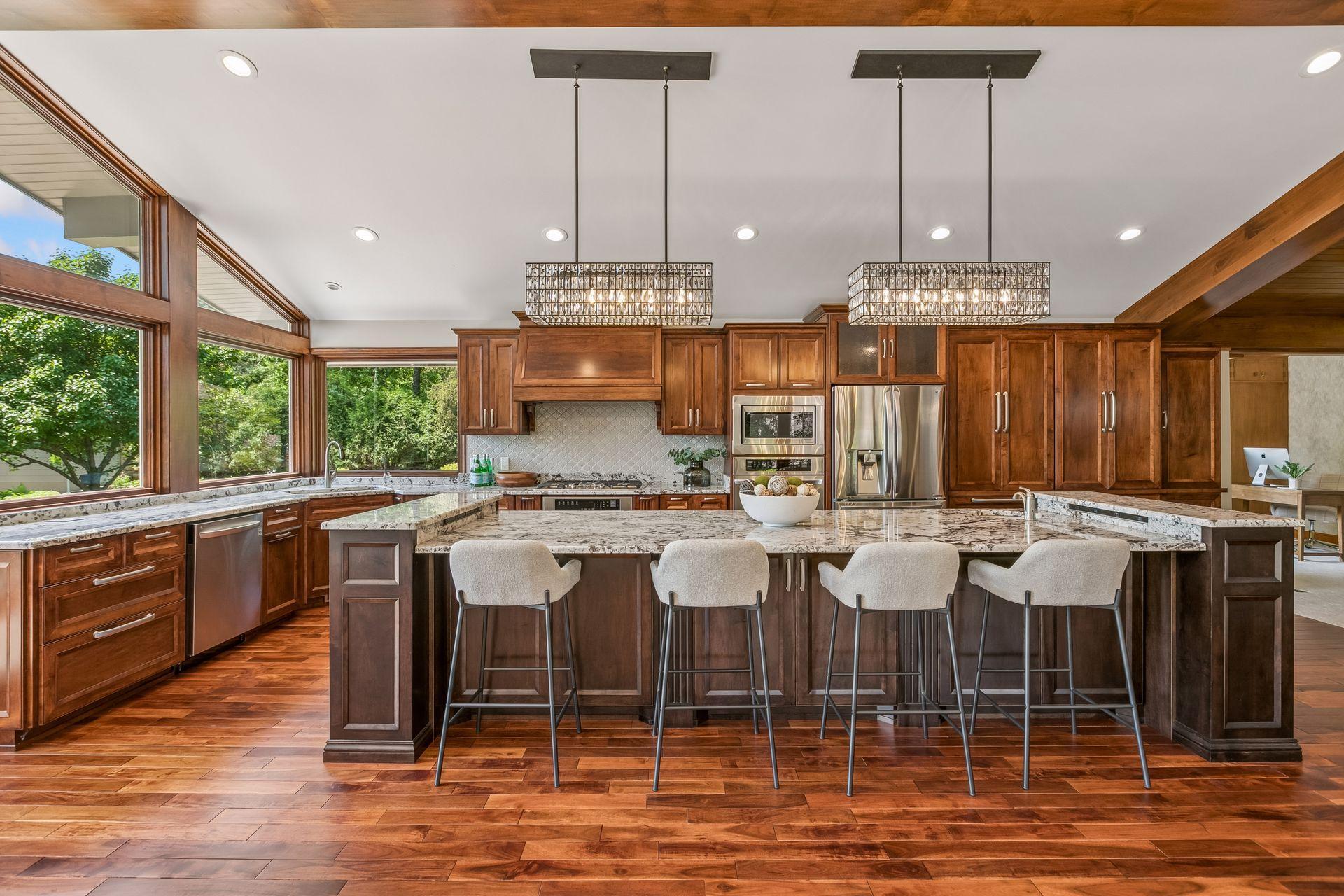 Kitchen with cherry cabinetry, granite island, stainless steel appliances, and large windows overlooking greenery.