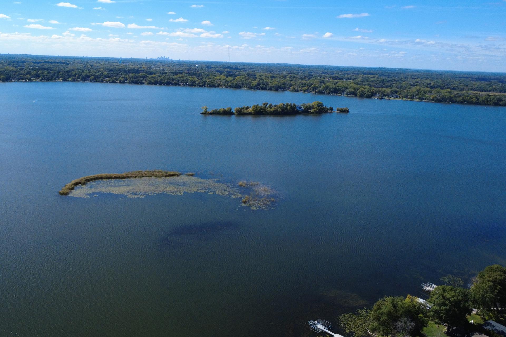 Aerial lake view with wooded islands and docks along the tree-lined shore.