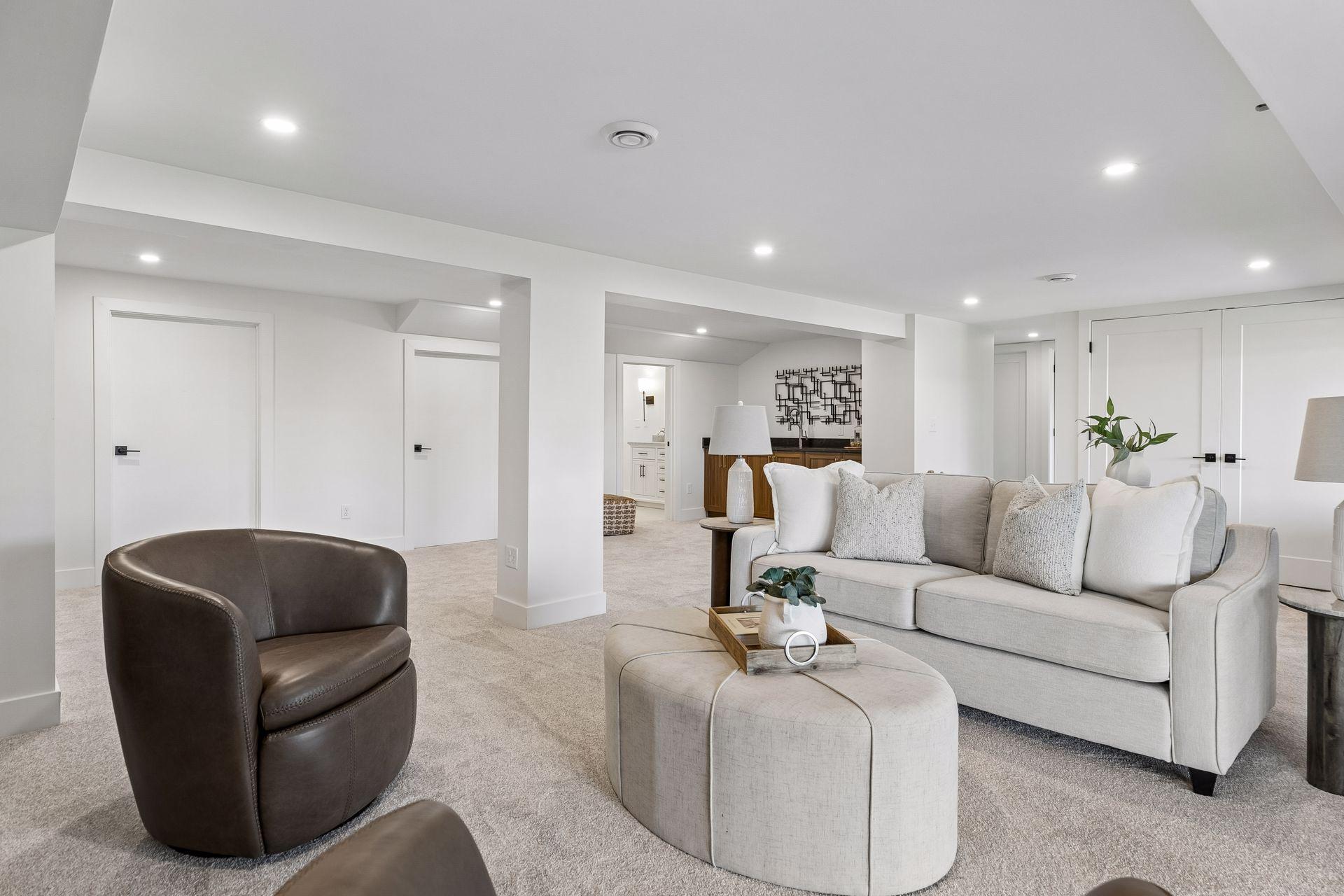 Staged living room with a gray sofa, leather armchair, and carpeted open layout.
