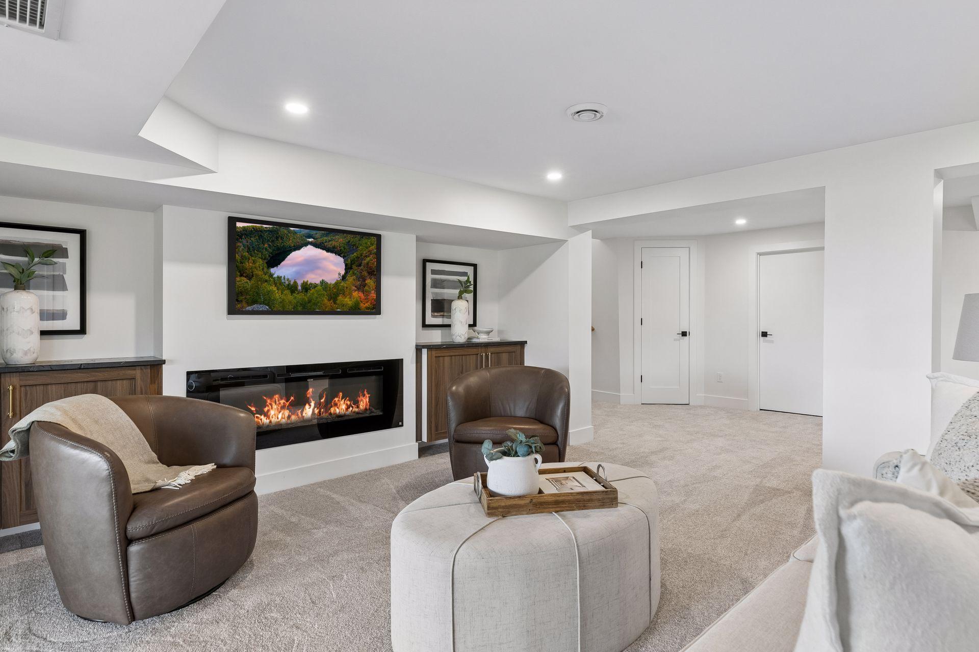 Living room with a wide modern fireplace, brown leather chairs, and built-in wood cabinetry.