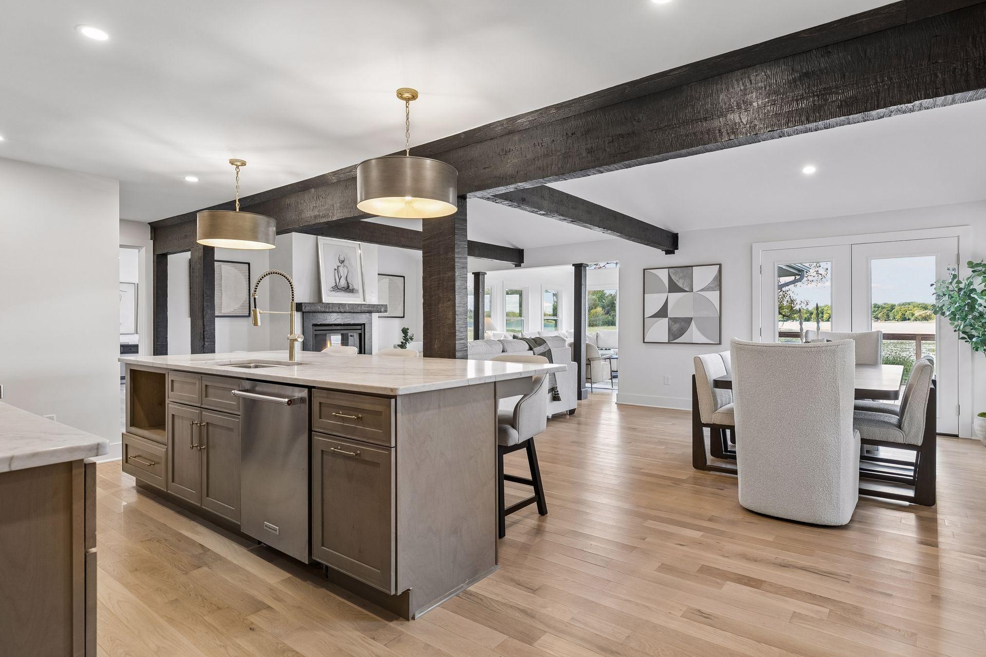 Open kitchen and dining area with a marble island, dark timber beams, and lake views through the windows.