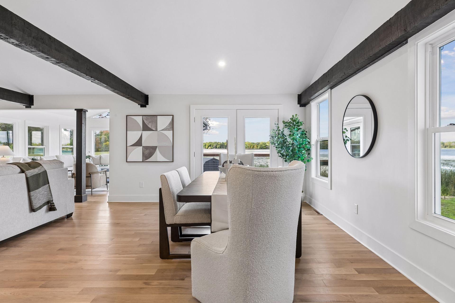 Open-plan dining area with exposed beams and lake views through large windows.
