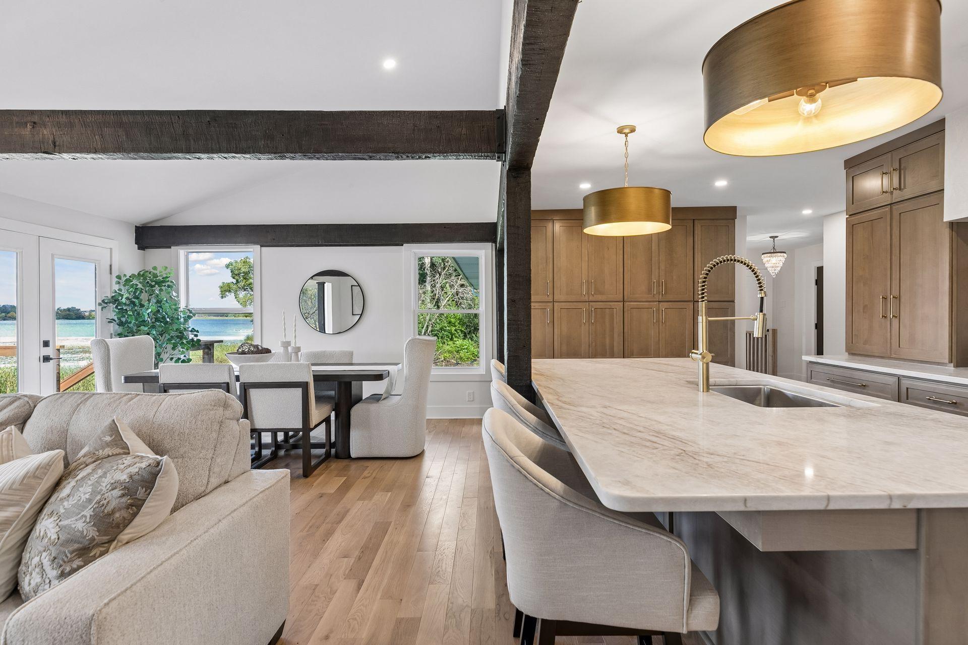 Open-plan kitchen and dining area with a large island, dark beams, and lake views through the windows.