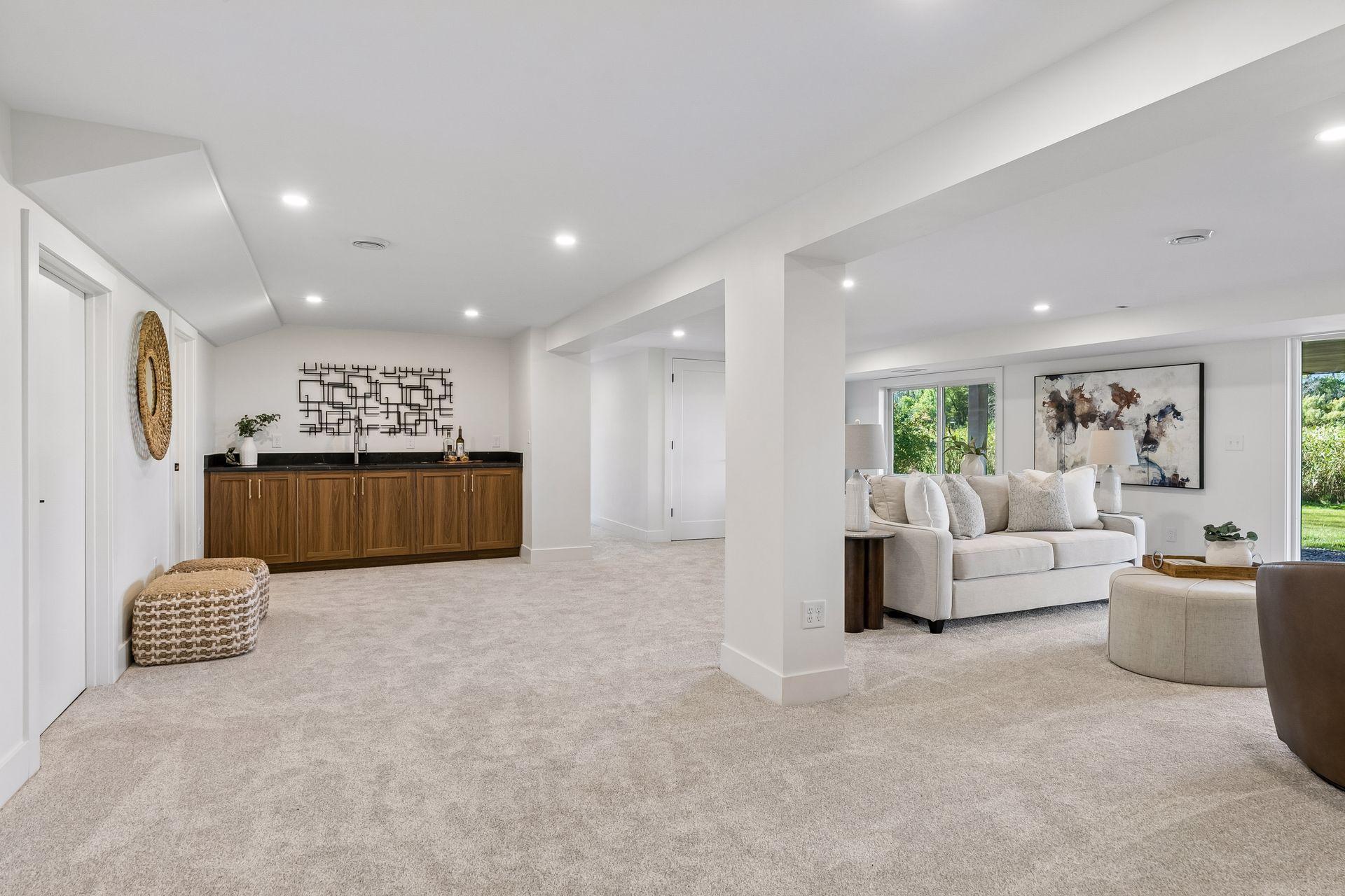 Carpeted living area with a wood-cabinet wet bar and a furnished lounge beside large windows.