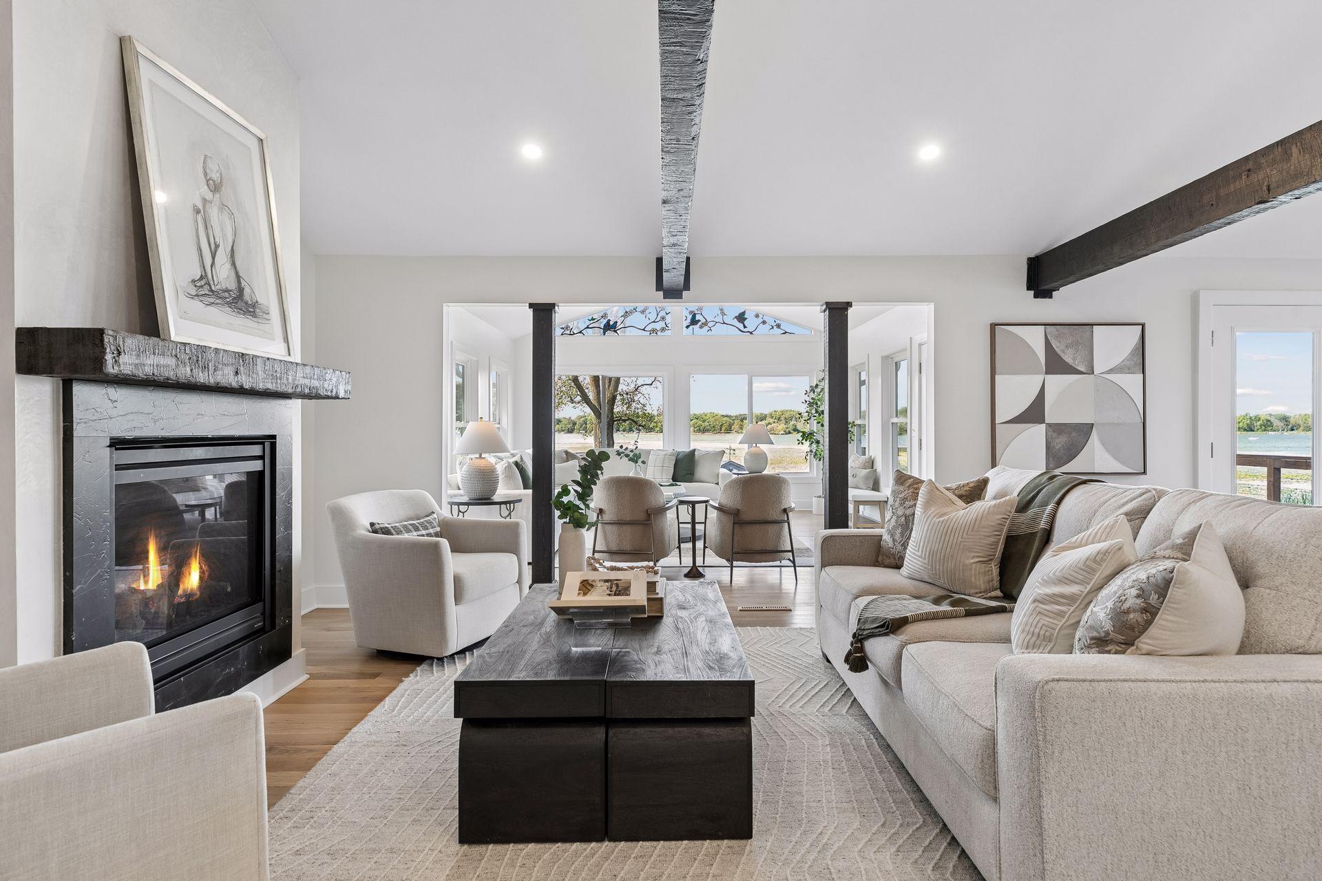 Living room with a fireplace, exposed beams, and lake views through the windows.