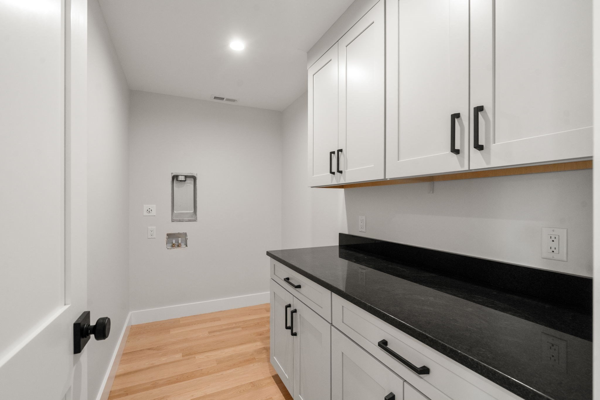 Laundry room with white cabinets, black countertop, and washer hookups.