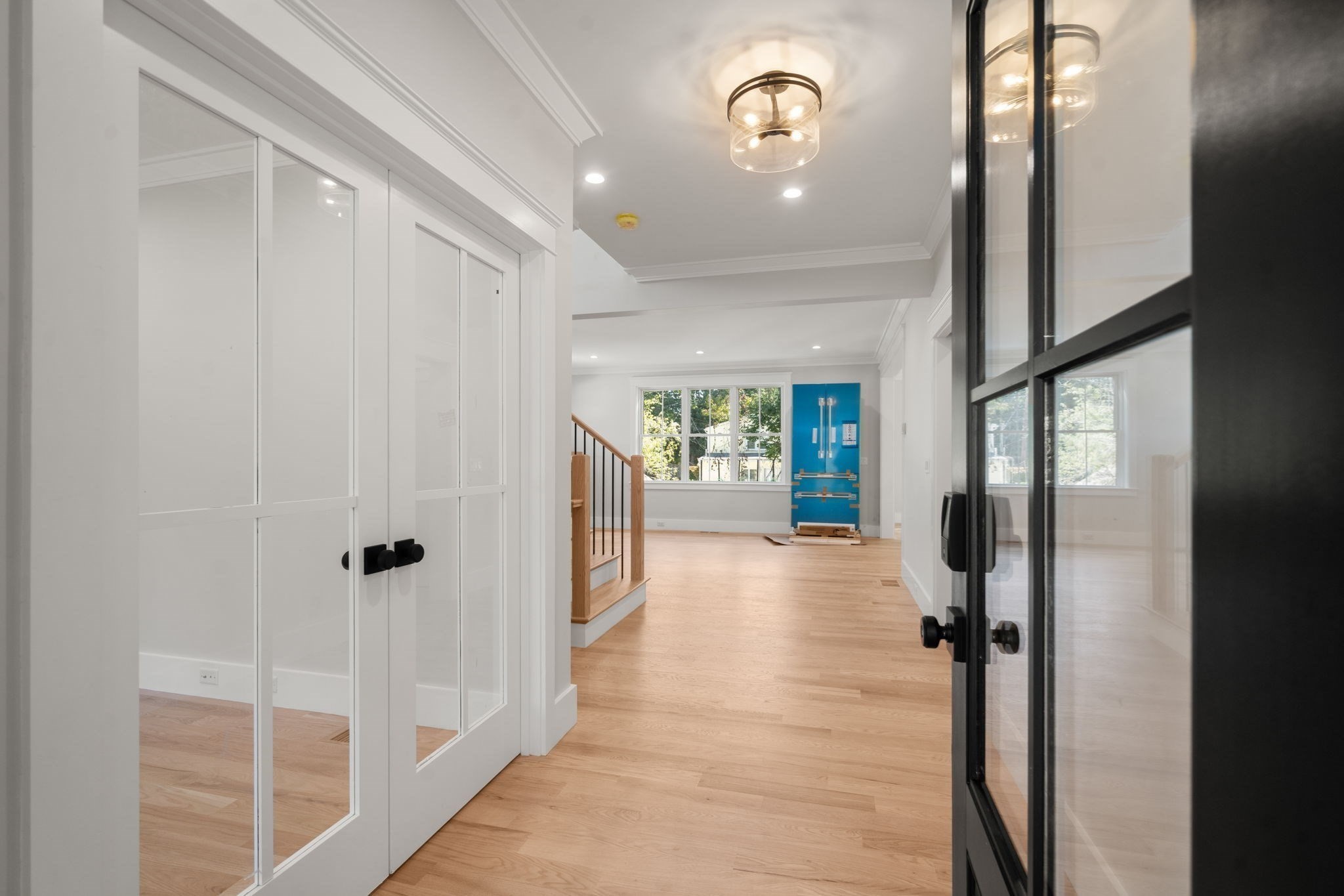Open interior with glass-paneled doors, hardwood floors, a staircase, and a blue refrigerator.