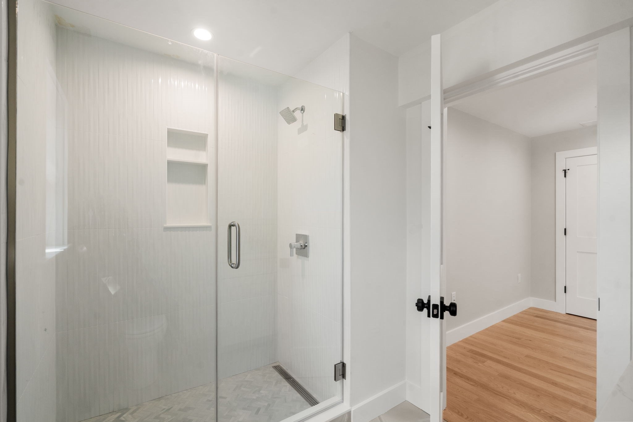 Modern bathroom with a glass-enclosed walk-in shower and built-in tiled niches.