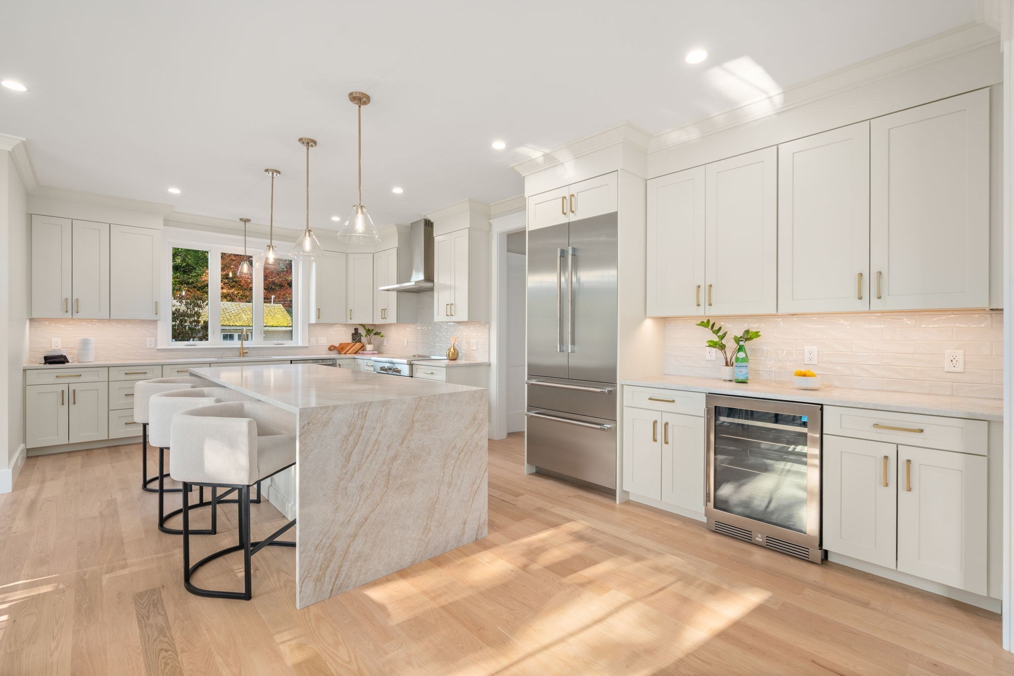 Modern kitchen with a marble waterfall island, white cabinetry, and stainless steel appliances.