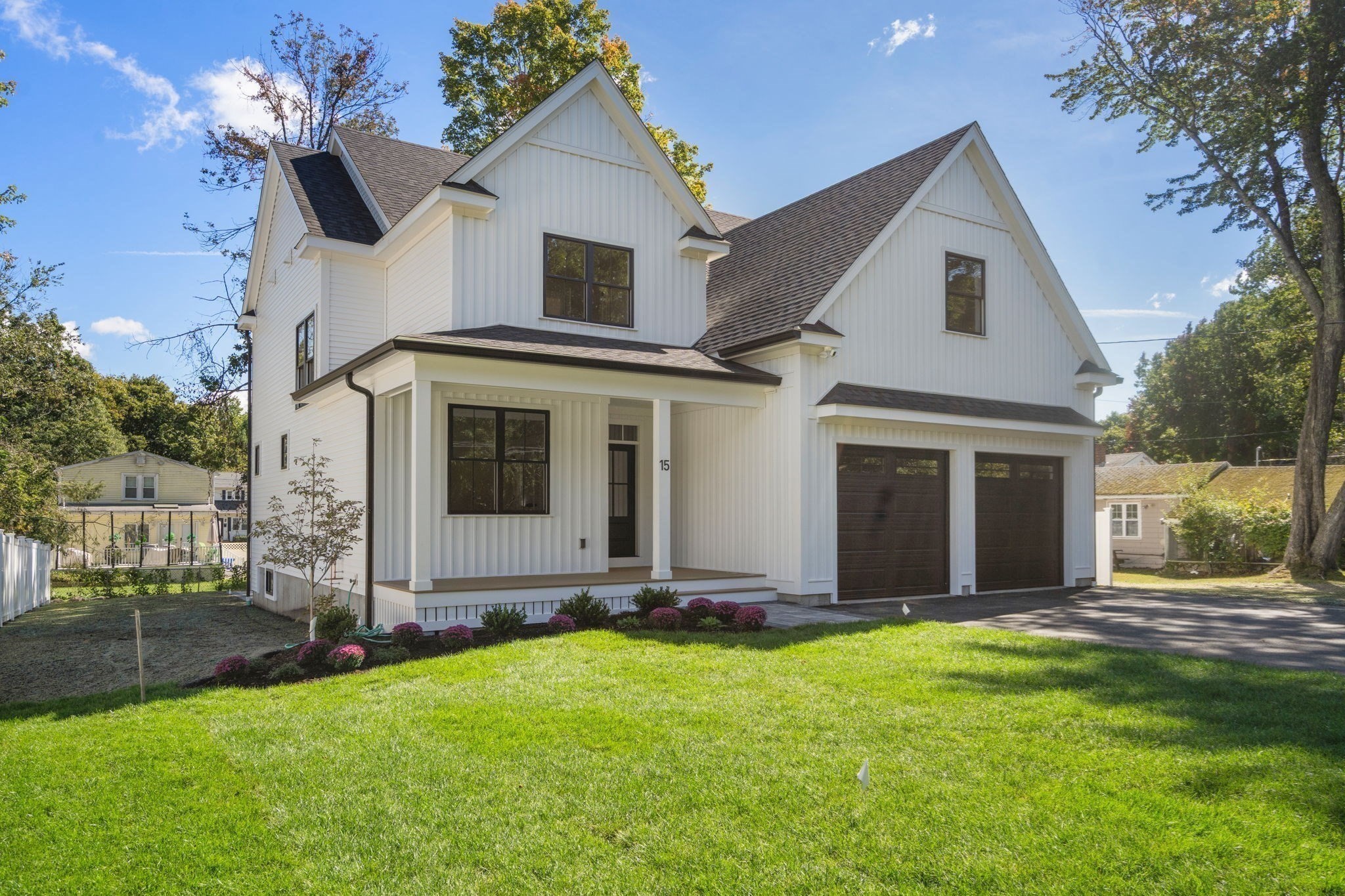 White two-story home with steep gables, a covered entry, and a dark double garage.