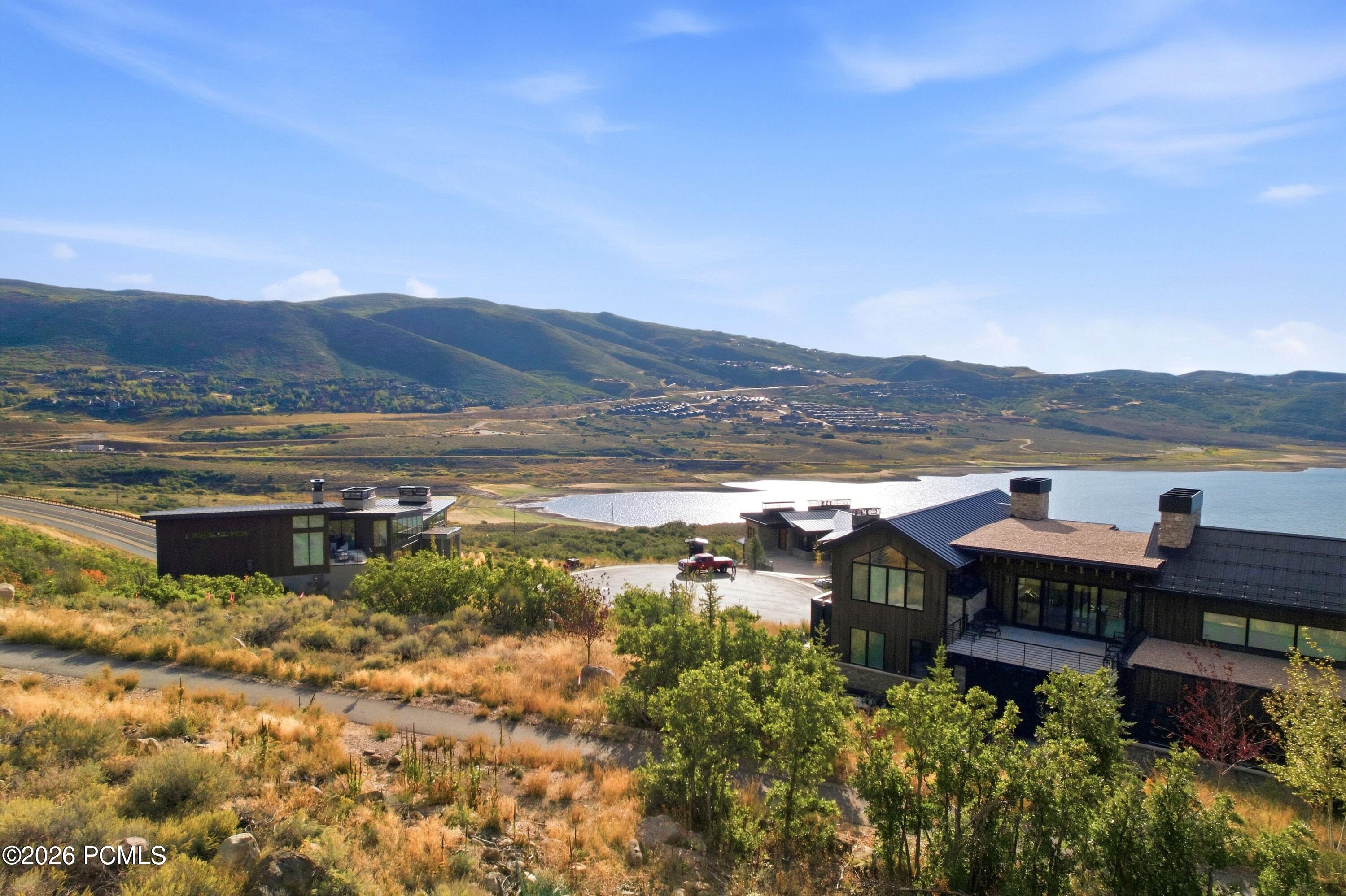 Modern hillside homes overlook a lake and rolling mountains.